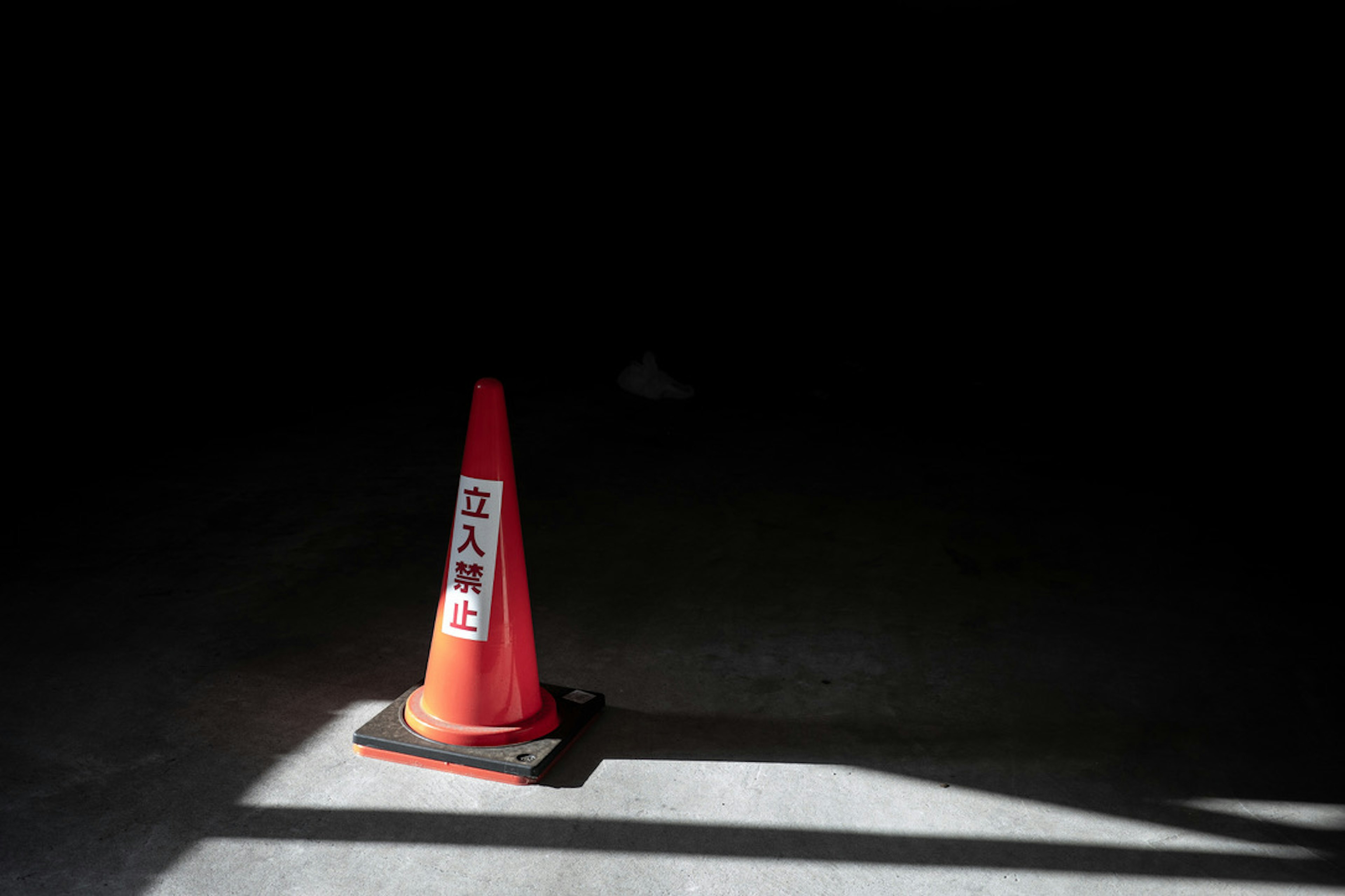 Un cono de tráfico rojo con un signo de prohibición en un espacio oscuro