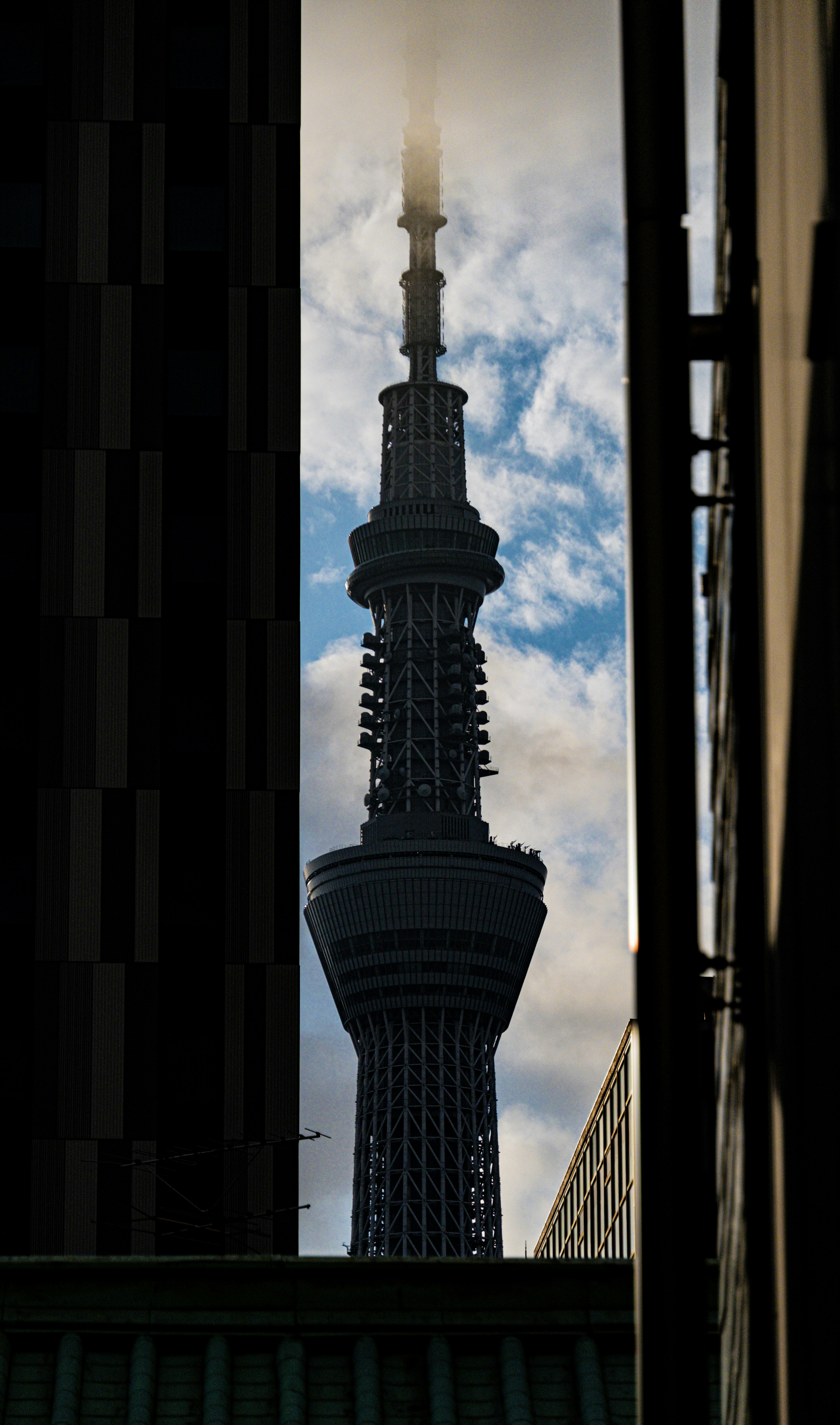 Tokyo Skytree se dressant à travers une étroite ouverture avec des nuages en arrière-plan