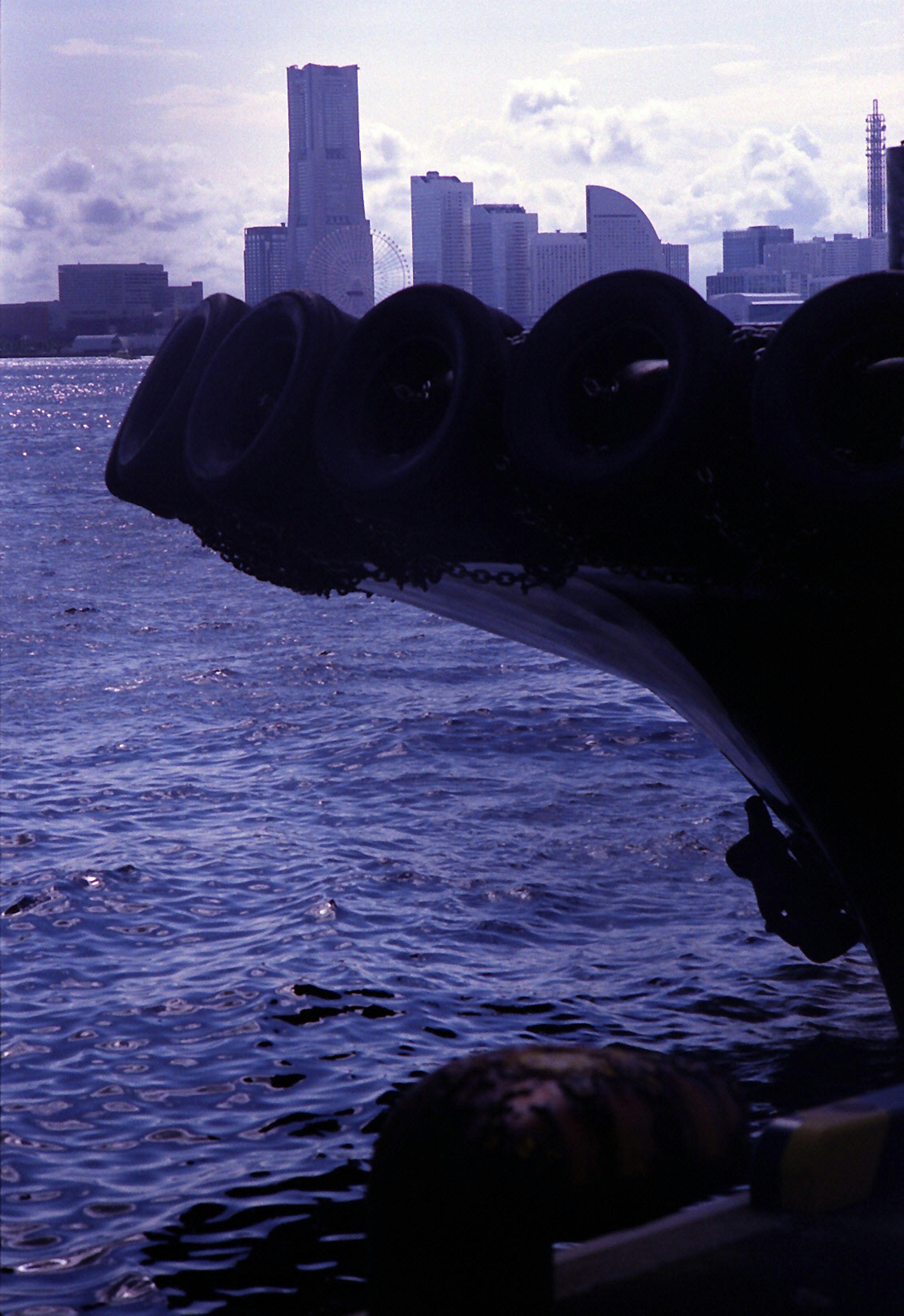 Bow of a ship with tires against a city skyline in the background