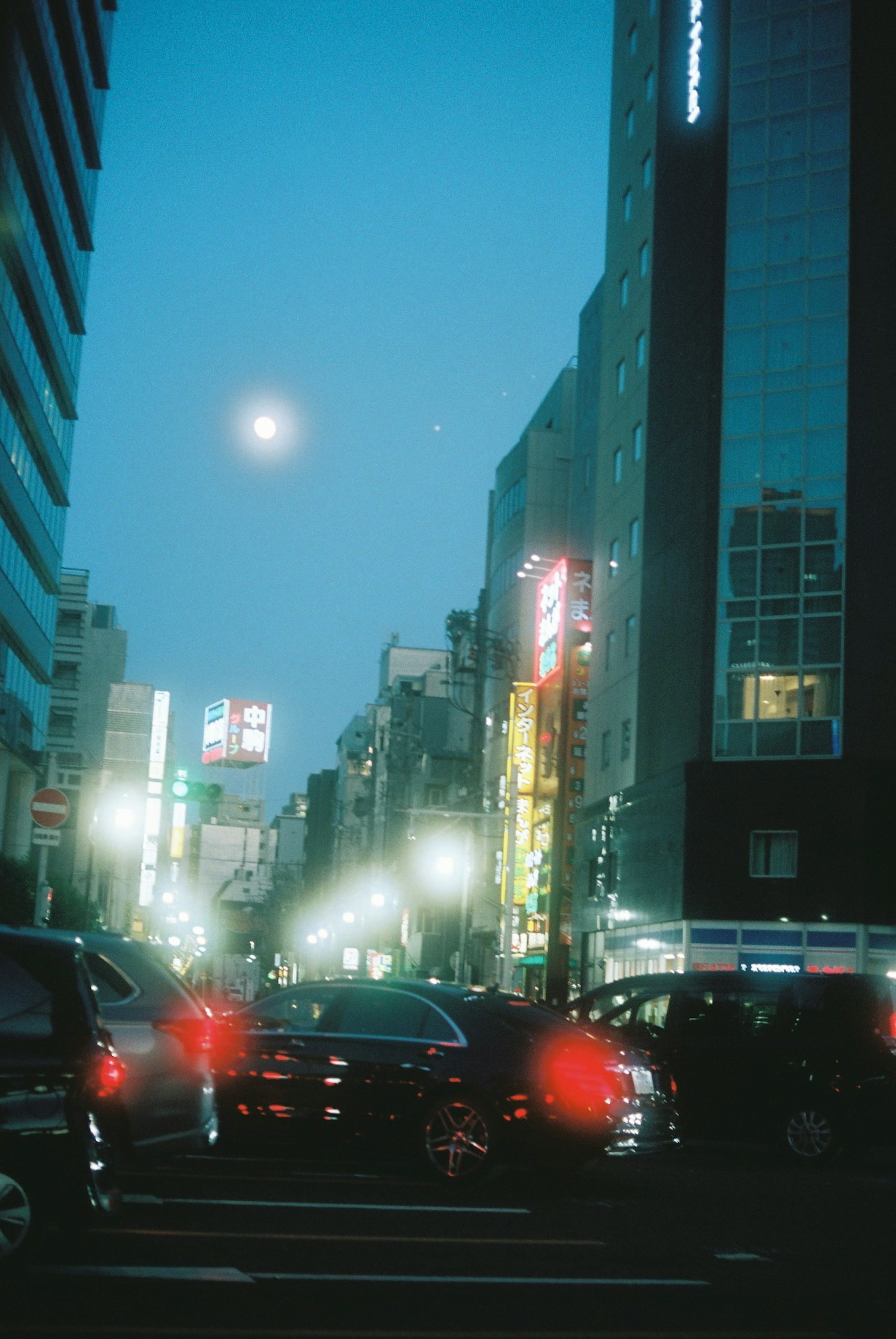 夜の都市風景に輝く月と輝く看板