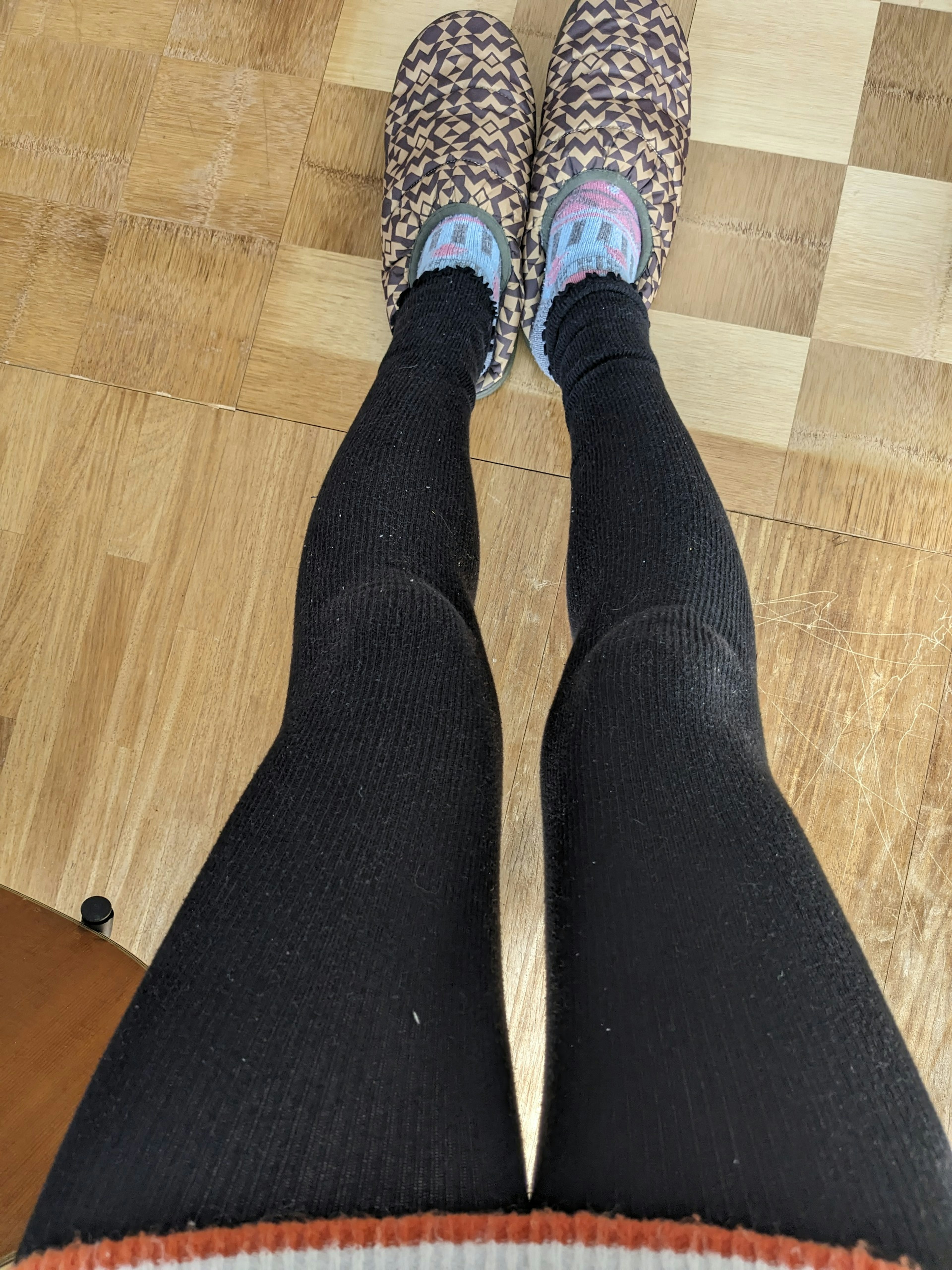 Photo of legs in black leggings and patterned slippers