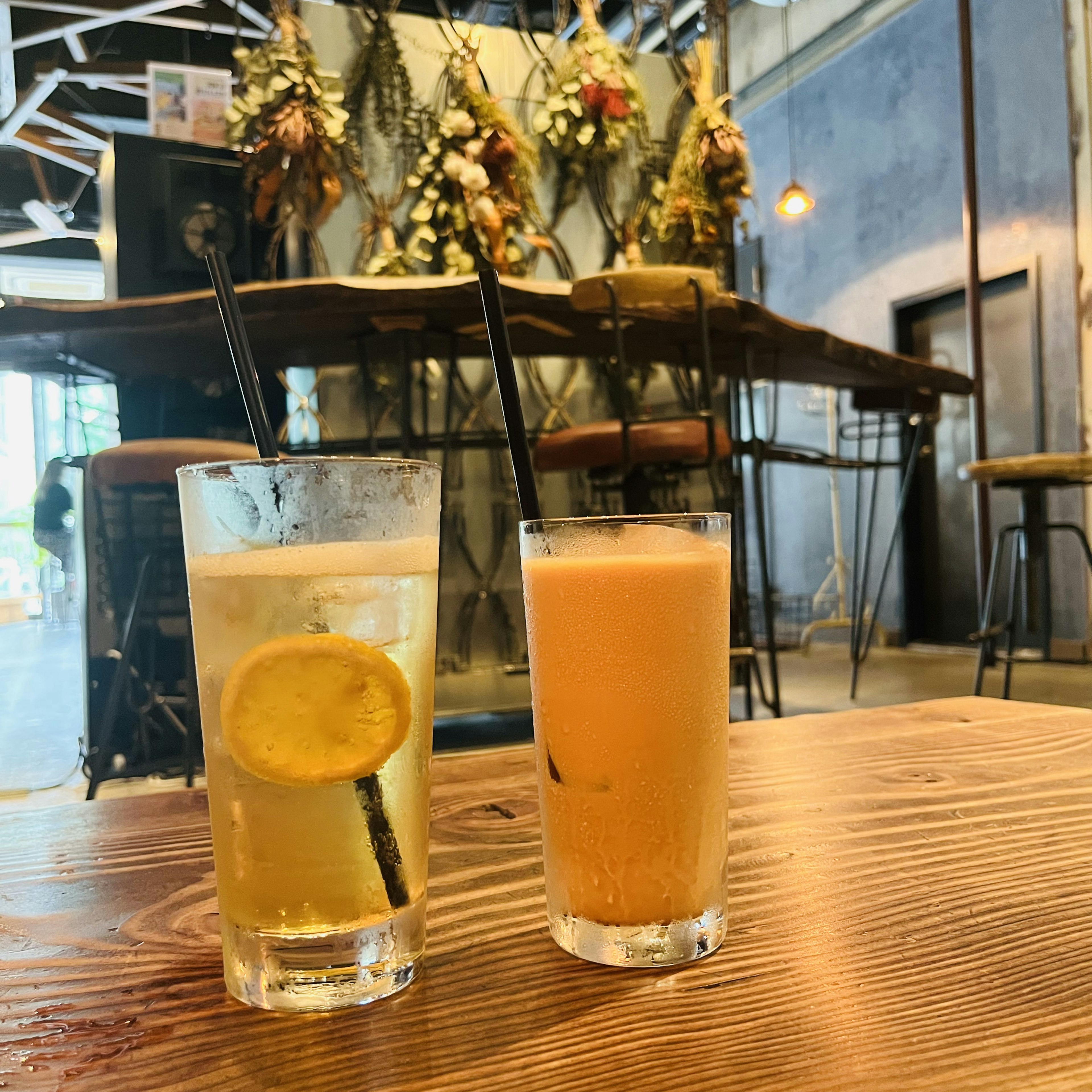 Dos bebidas en una mesa de madera una con limón y la otra naranja en un café elegante