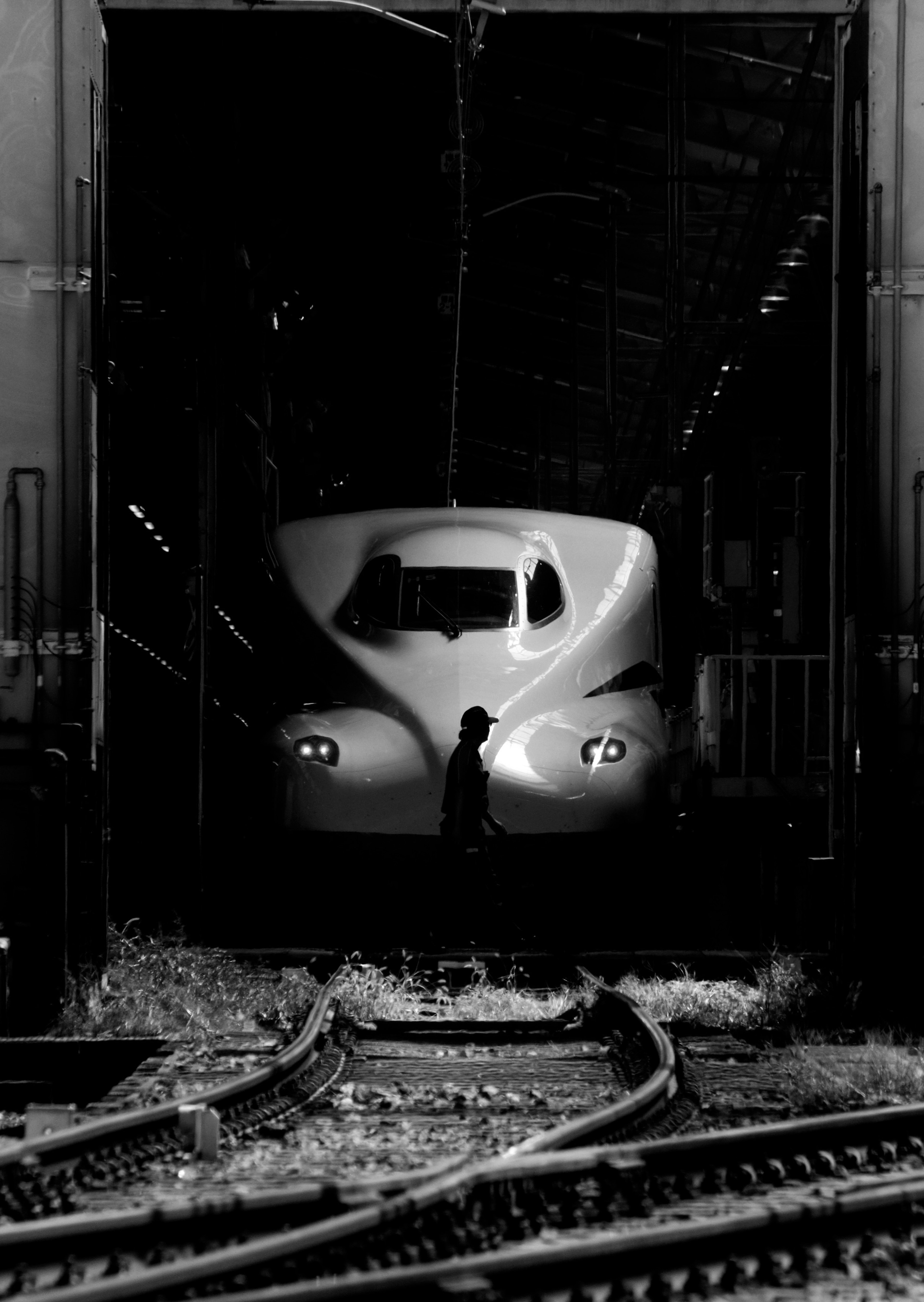 Train à grande vitesse en noir et blanc émergeant d'un tunnel avec des voies visibles