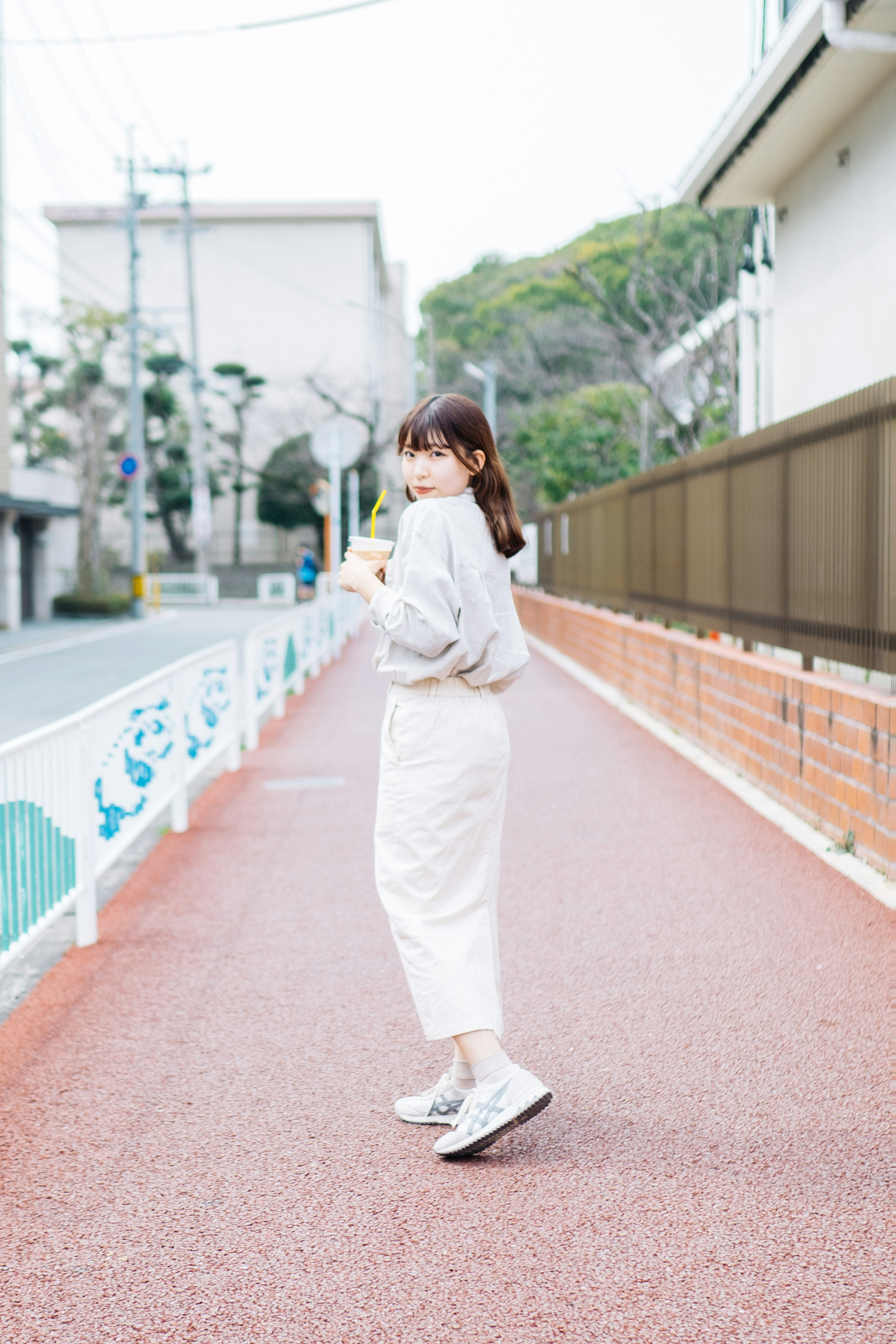 Une femme portant un sweat-shirt et un pantalon blanc marchant dans la rue