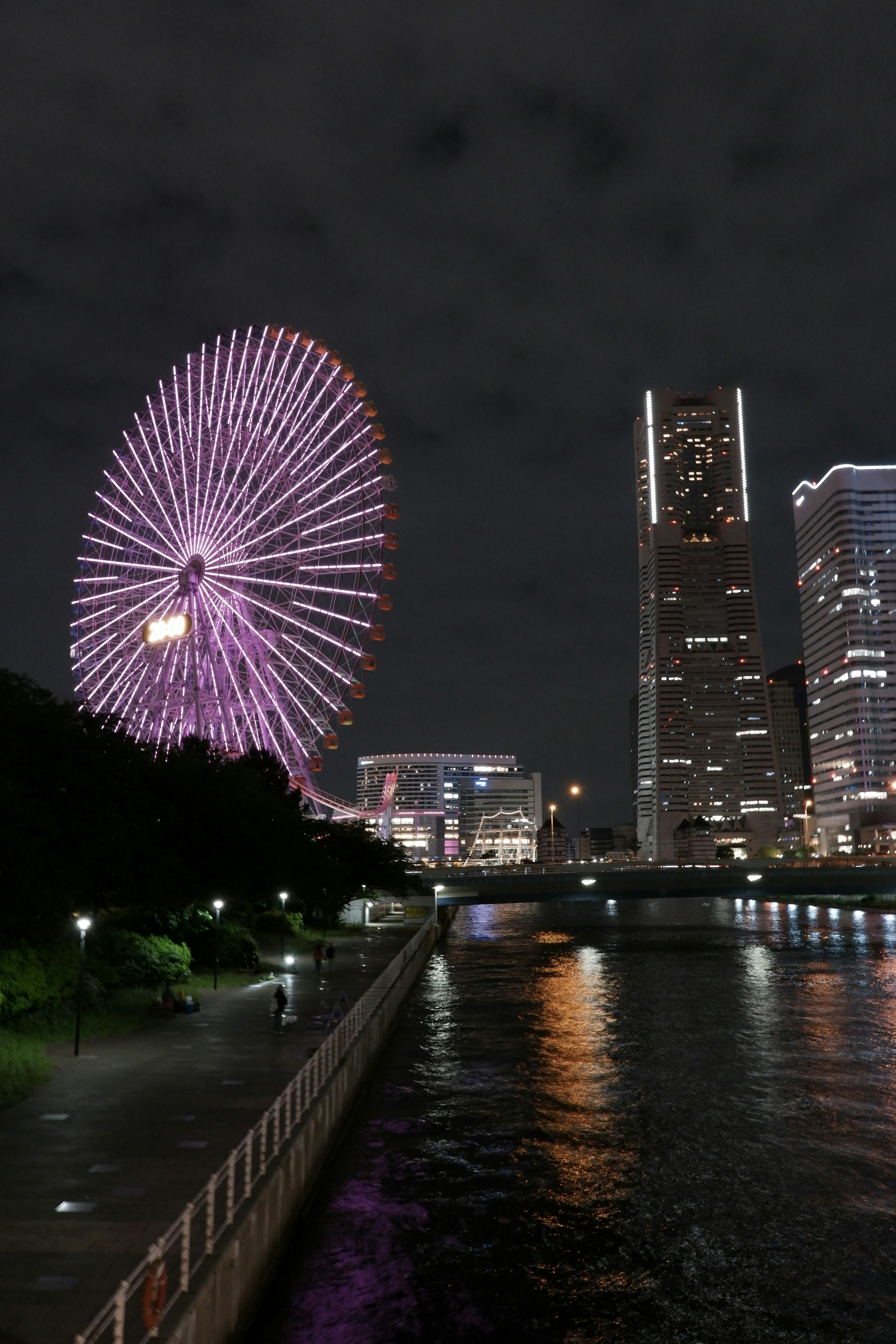 Roda Ferris yang diterangi dan gedung pencakar langit di Yokohama di malam hari