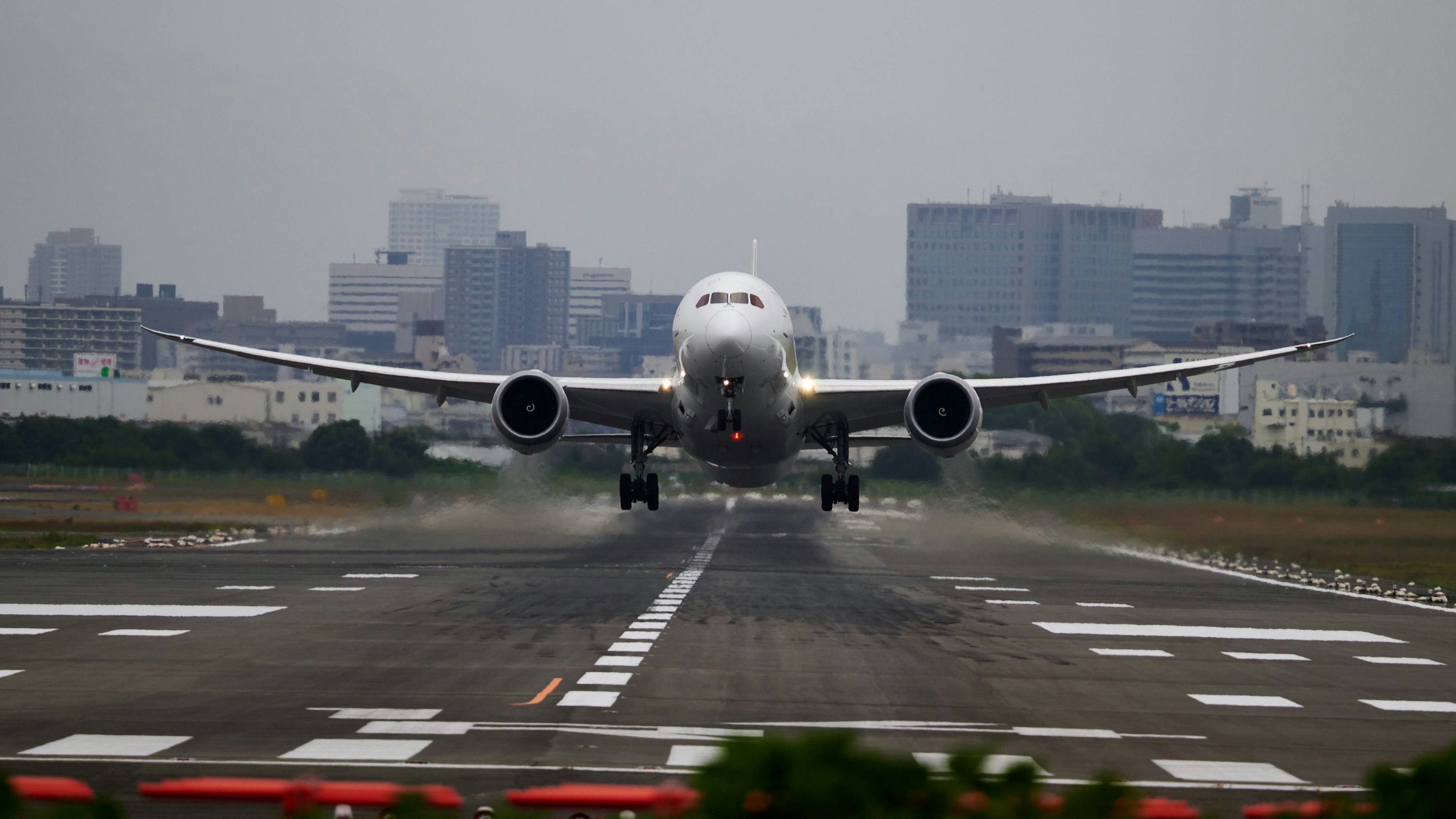 客機在跑道上降落，背景為城市天際線