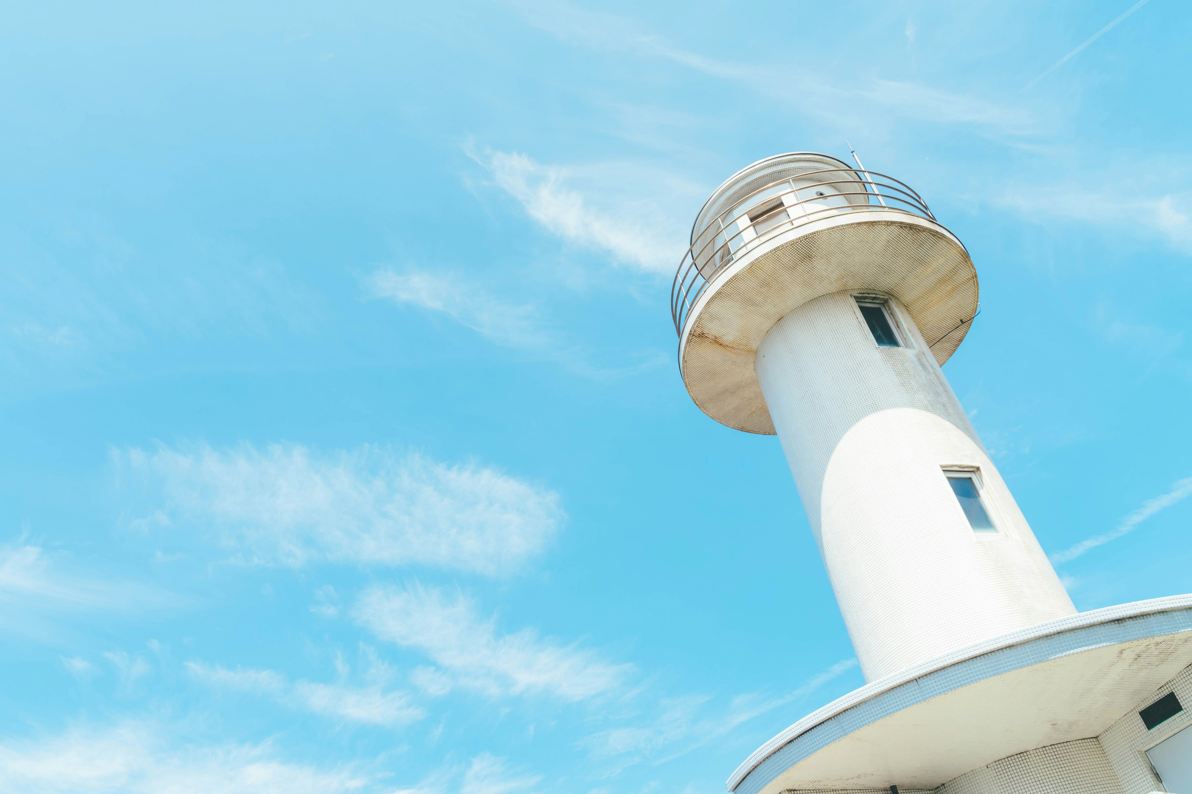 A white lighthouse under a blue sky