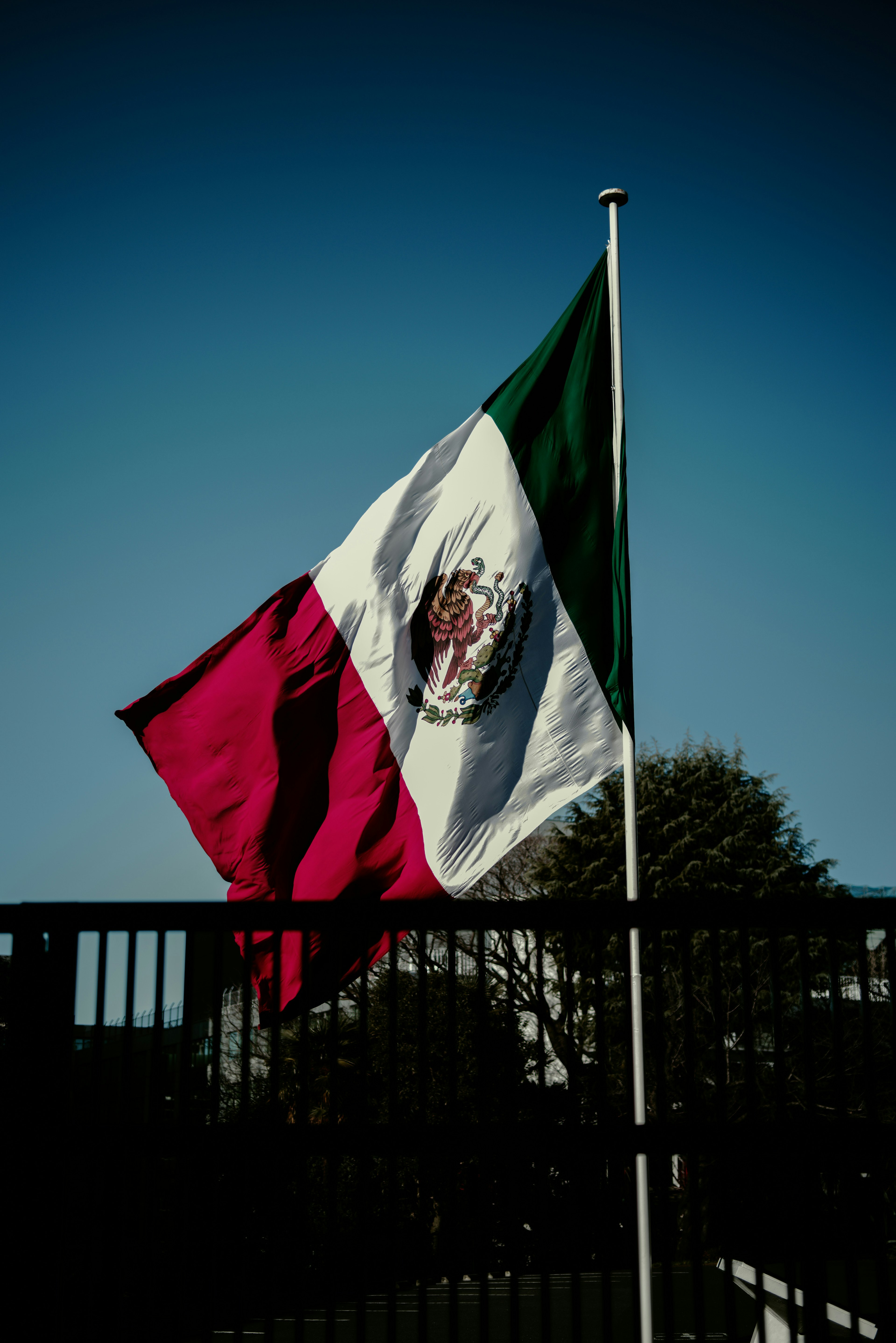 Bandera mexicana ondeando bajo un cielo azul