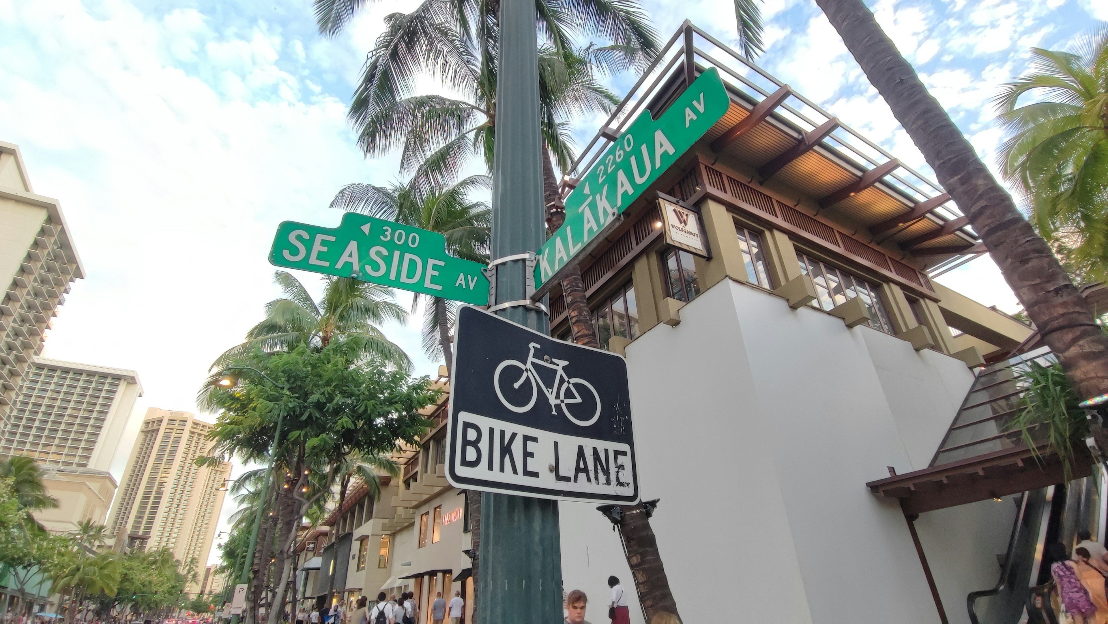 Panneaux de rue pour Seaside et Kalakaua avec un panneau de piste cyclable dans un cadre tropical