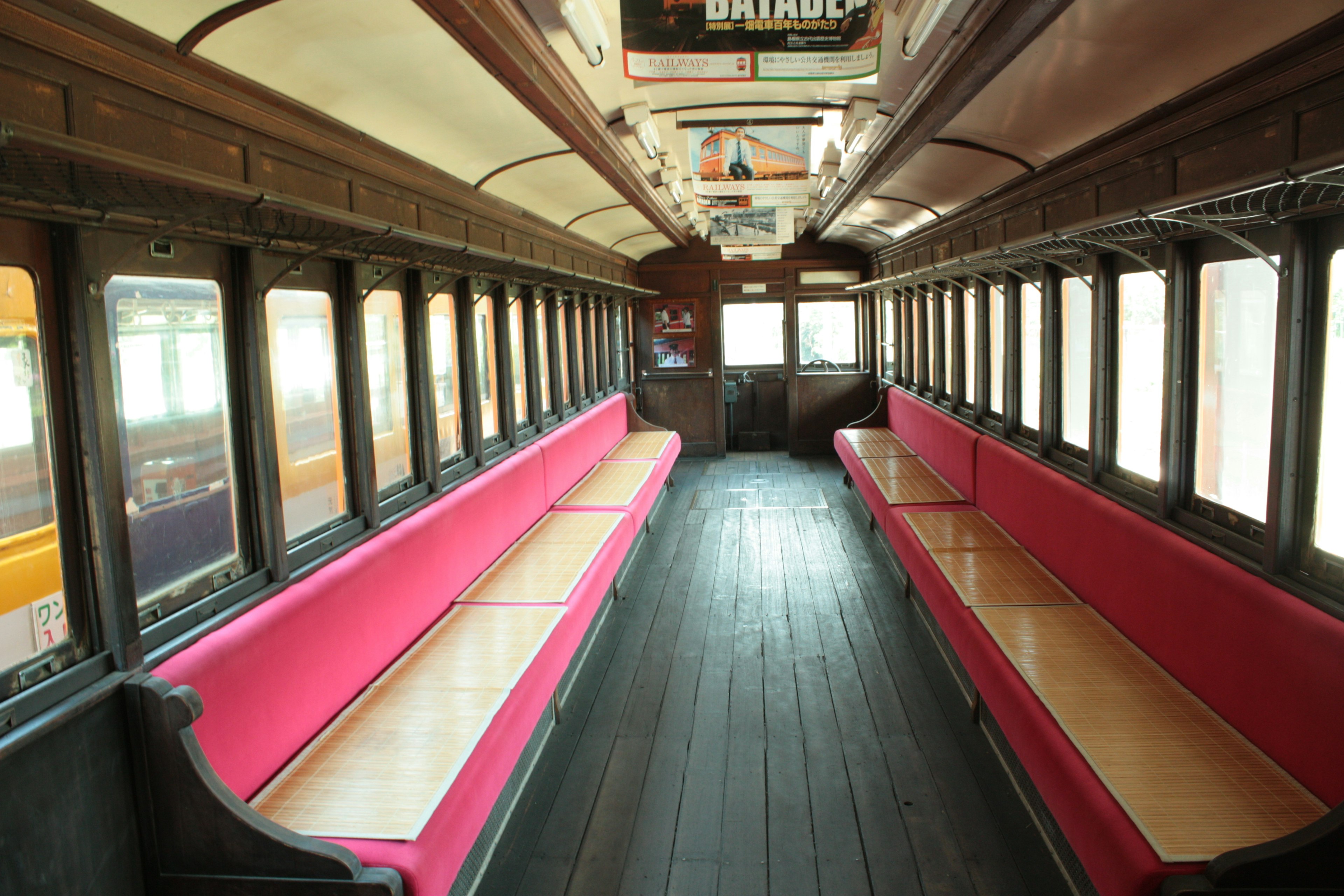 Intérieur d'un ancien wagon de train avec des bancs roses et un sol en bois