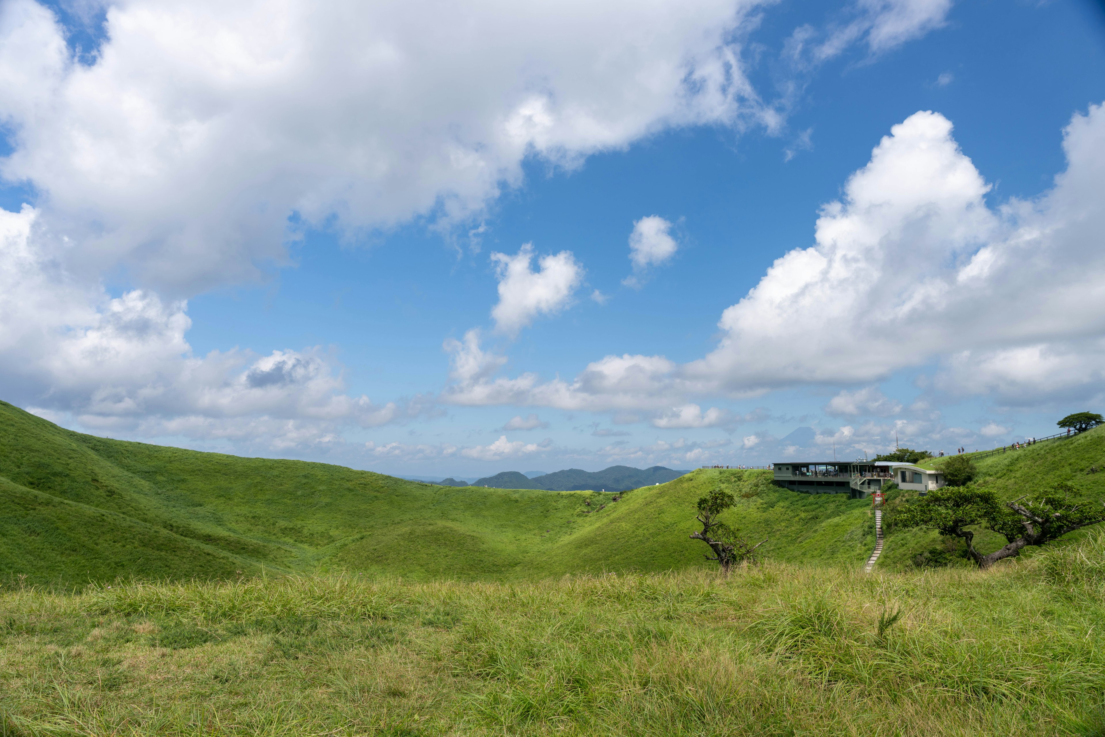 緑の丘と青い空の風景、白い雲が浮かぶ