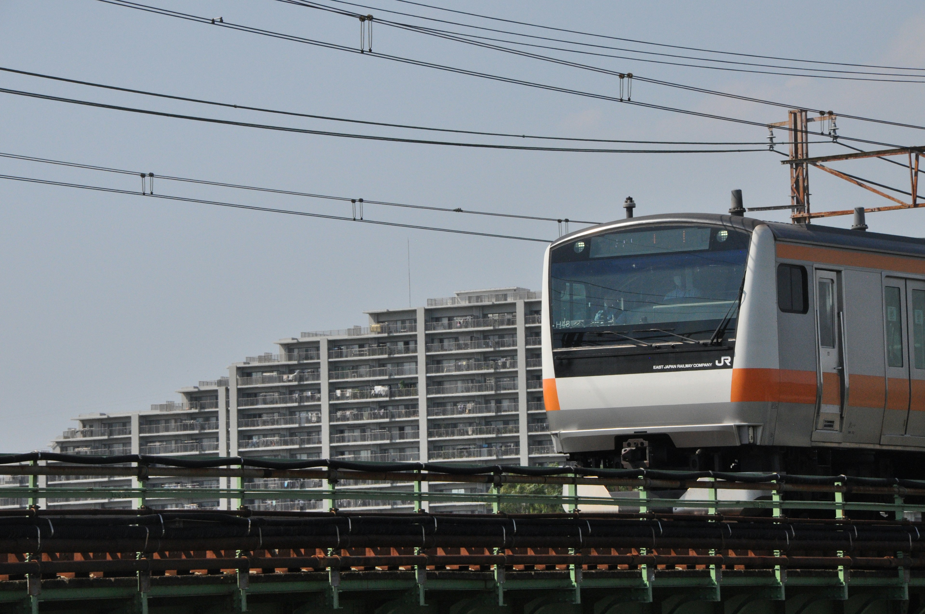 An orange and white train running on an elevated track Modern buildings in the background