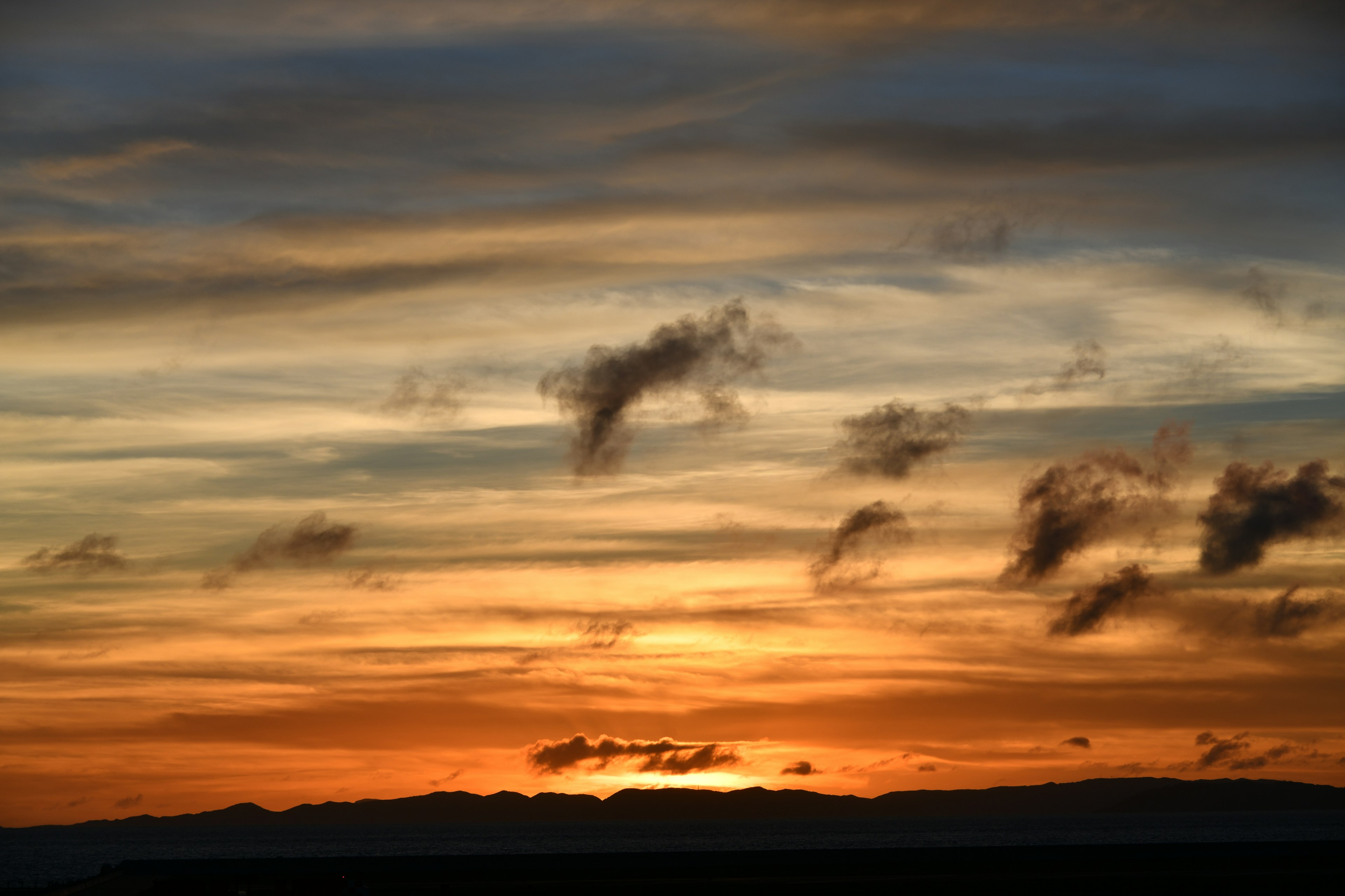 Tramonto con cielo arancione e blu e nuvole sottili