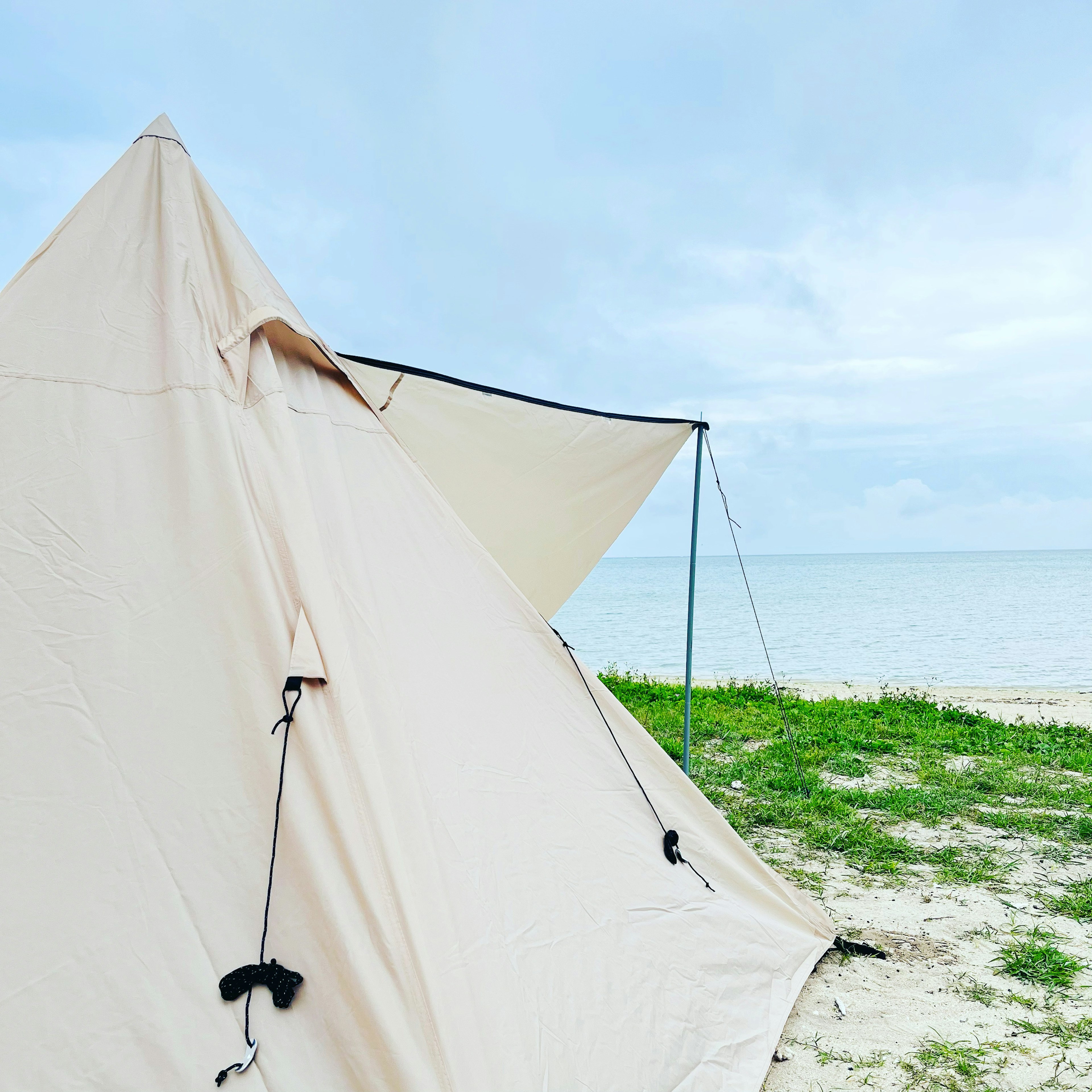 Tenda color crema sulla spiaggia con un oceano sereno sullo sfondo