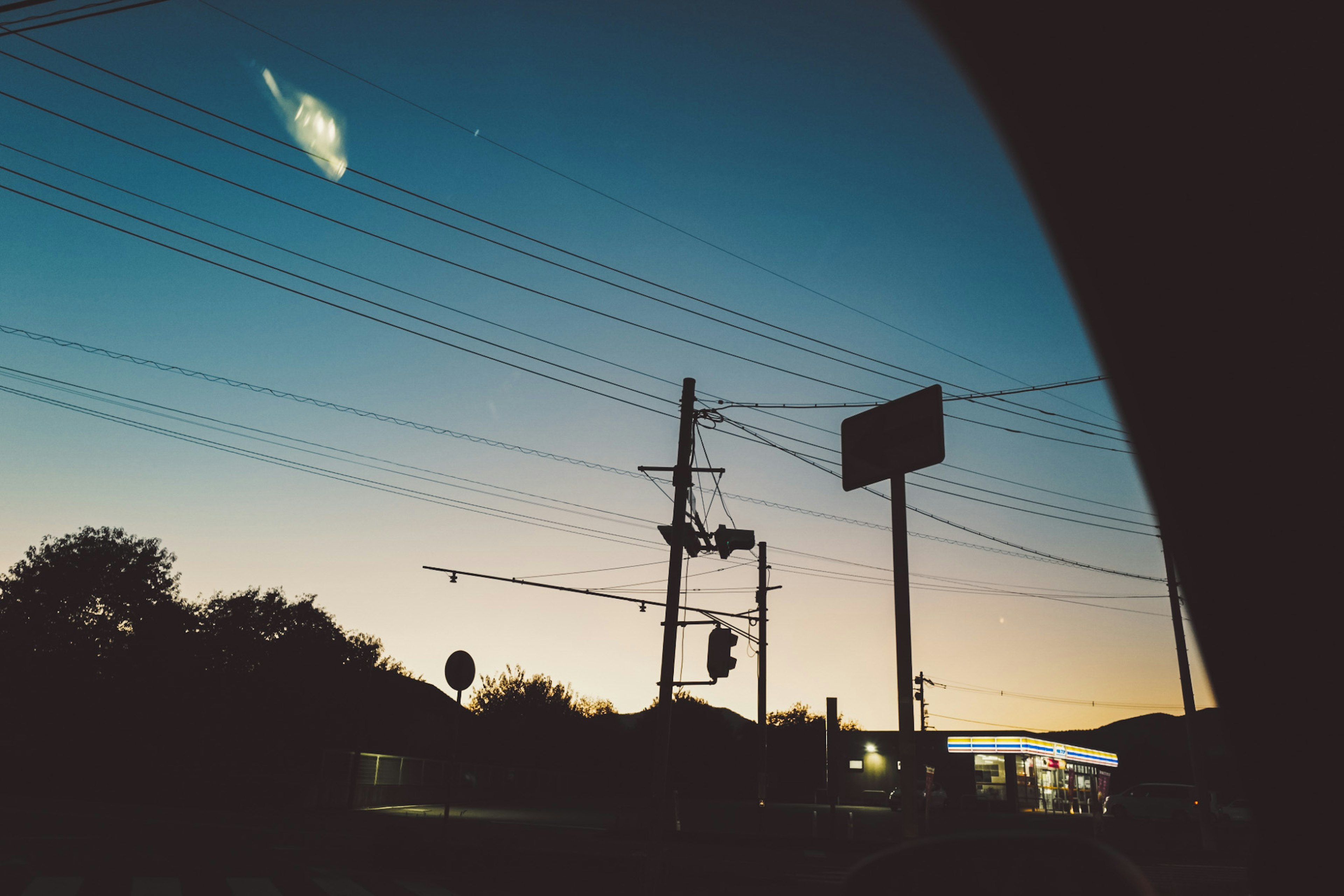 Evening cityscape with silhouetted houses and power lines gradient sky with blue and orange hues