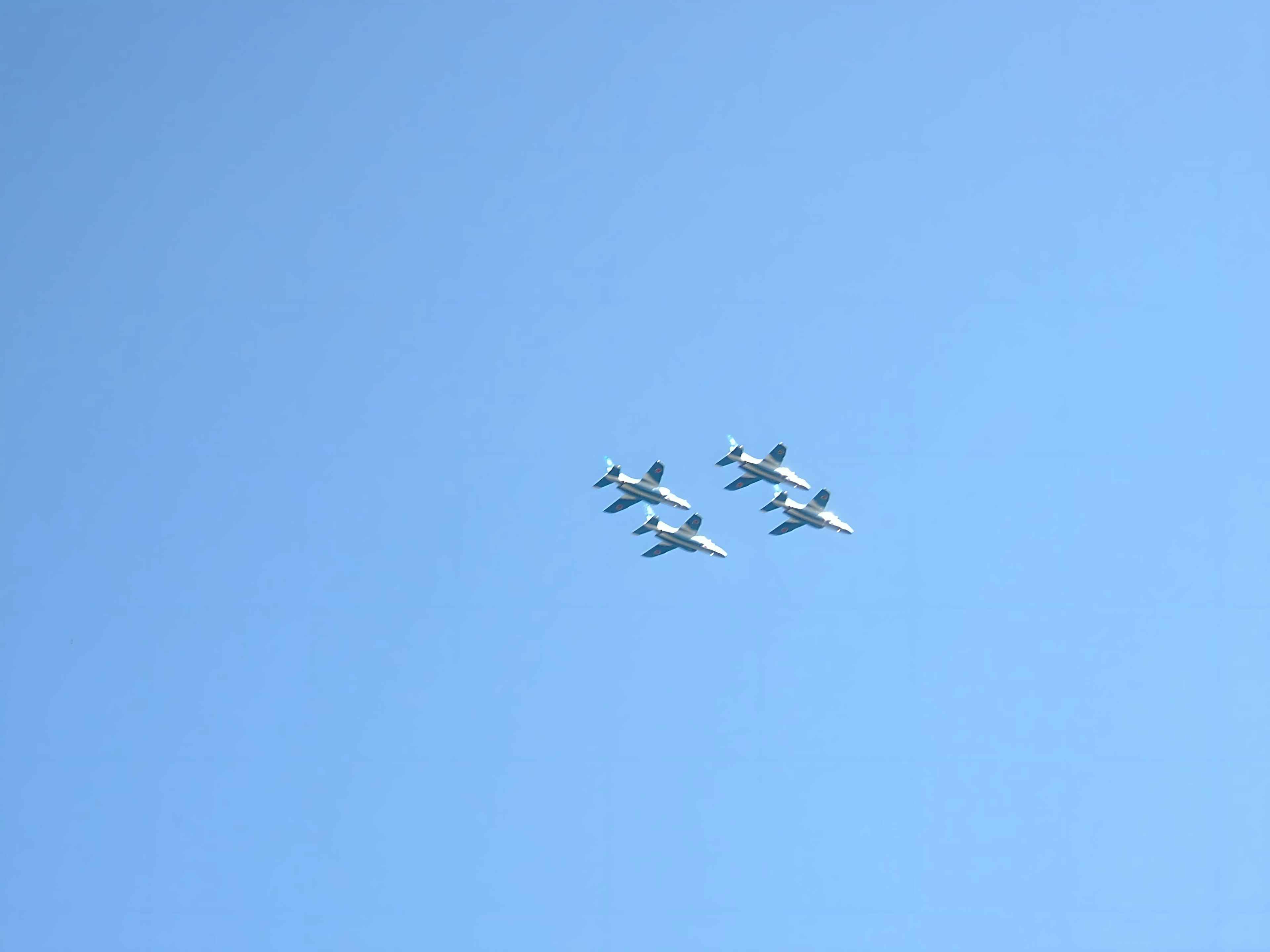 Formation of four fighter jets flying in a blue sky