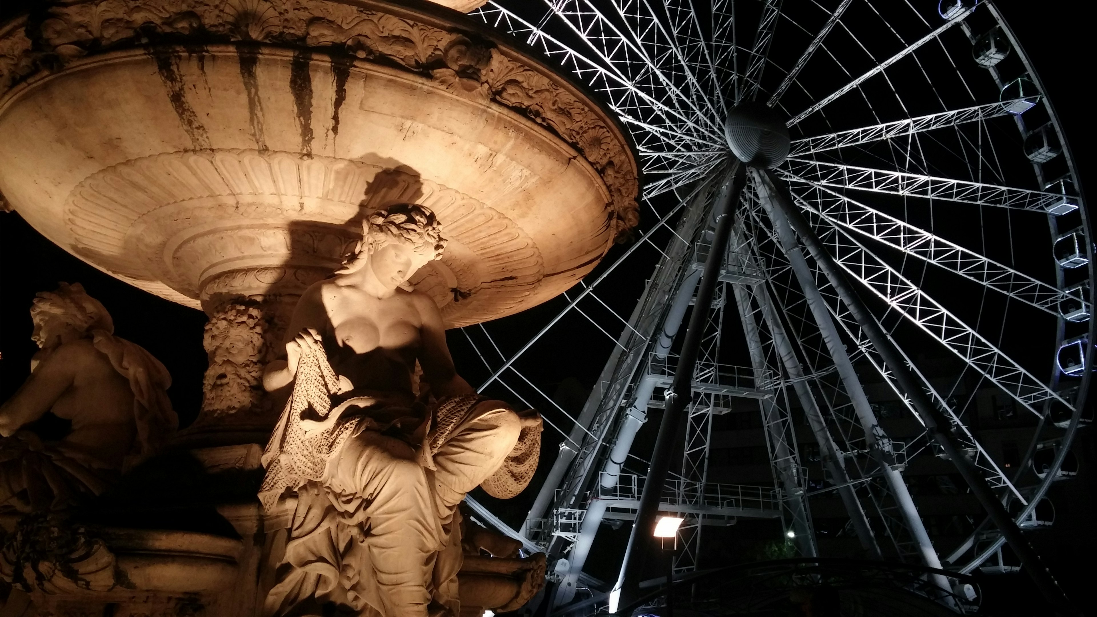 Pemandangan malam patung air mancur dengan roda ferris