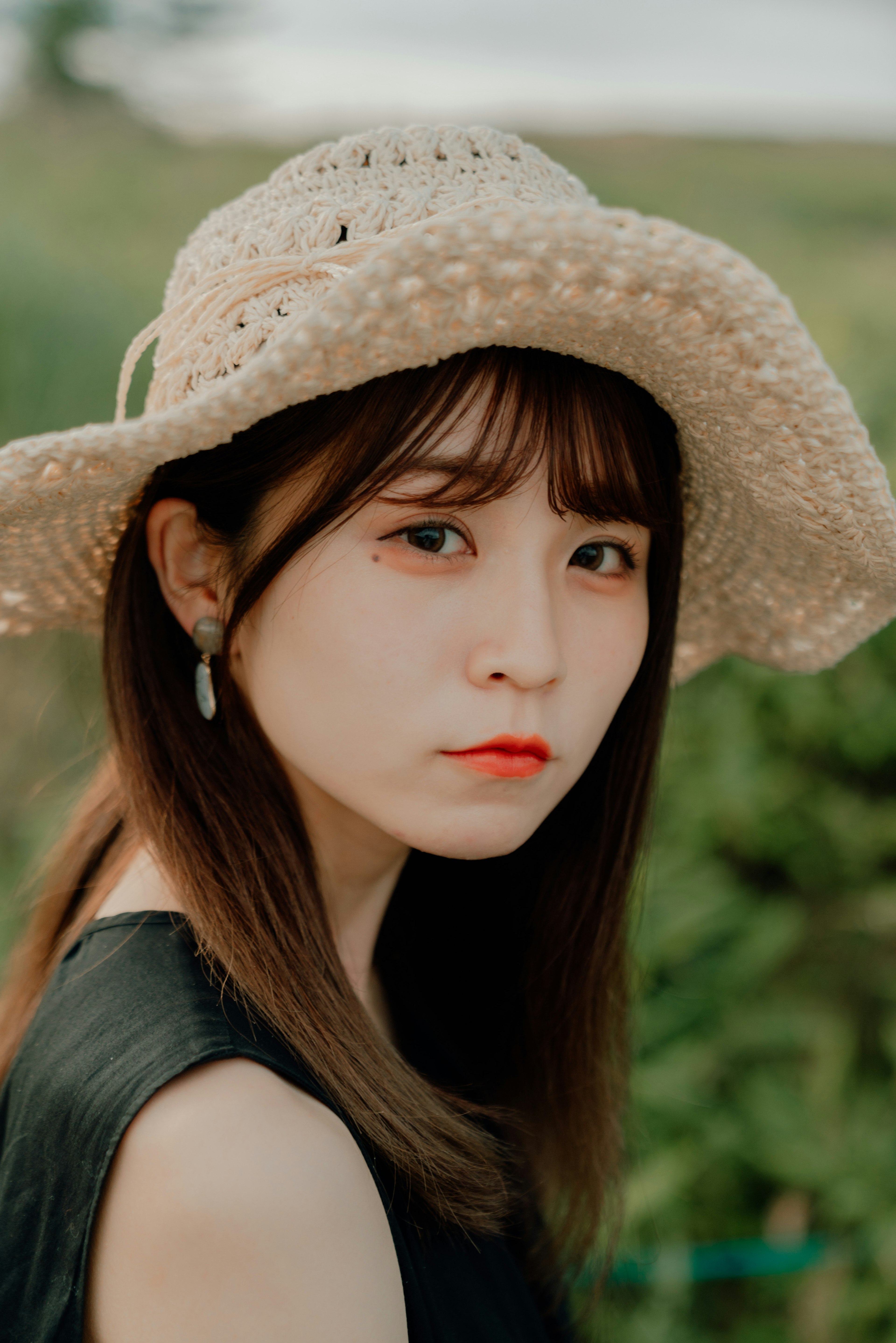 Portrait of a woman wearing a hat against a green background