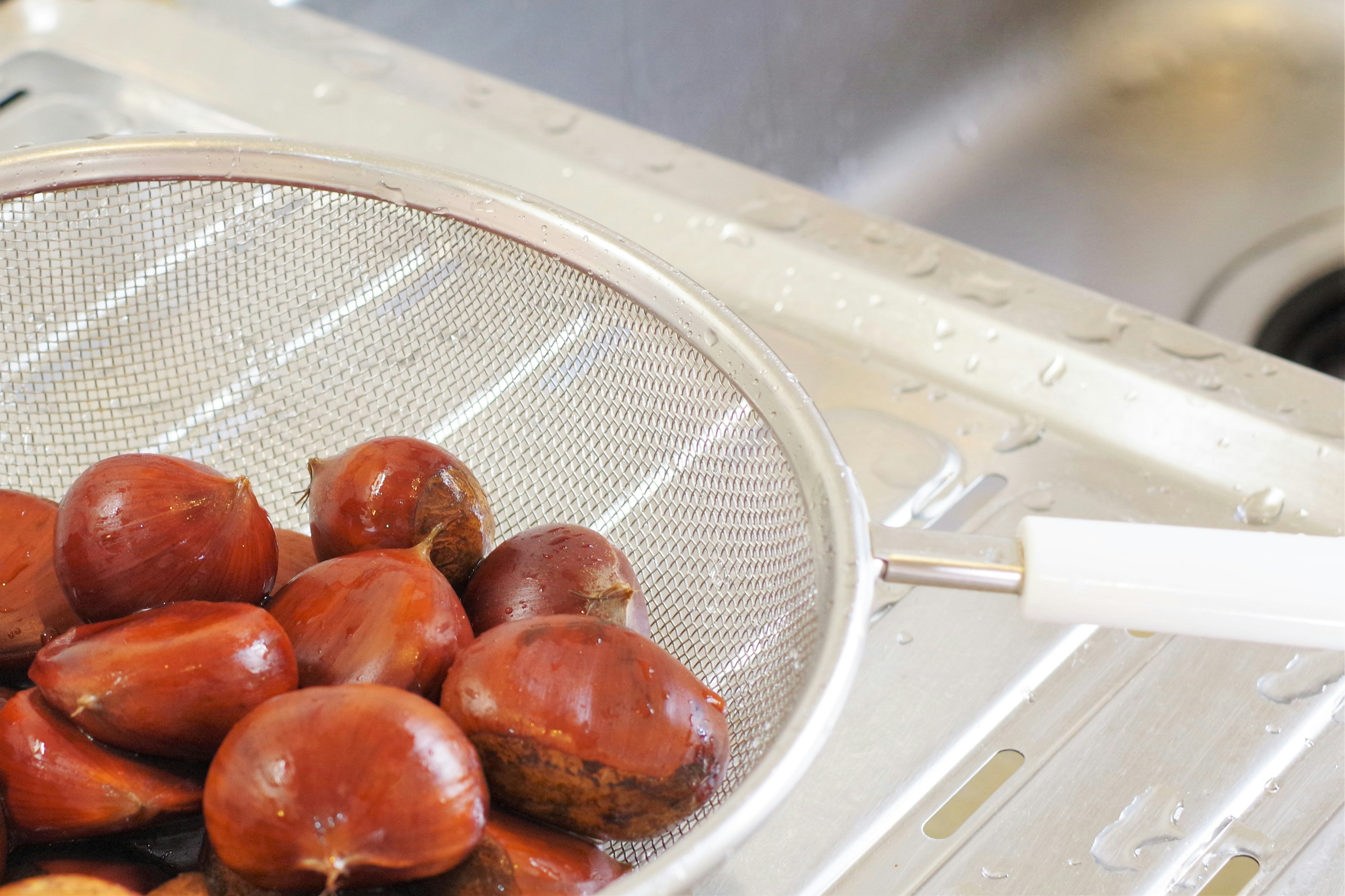 Chestnuts in a metal strainer over a sink