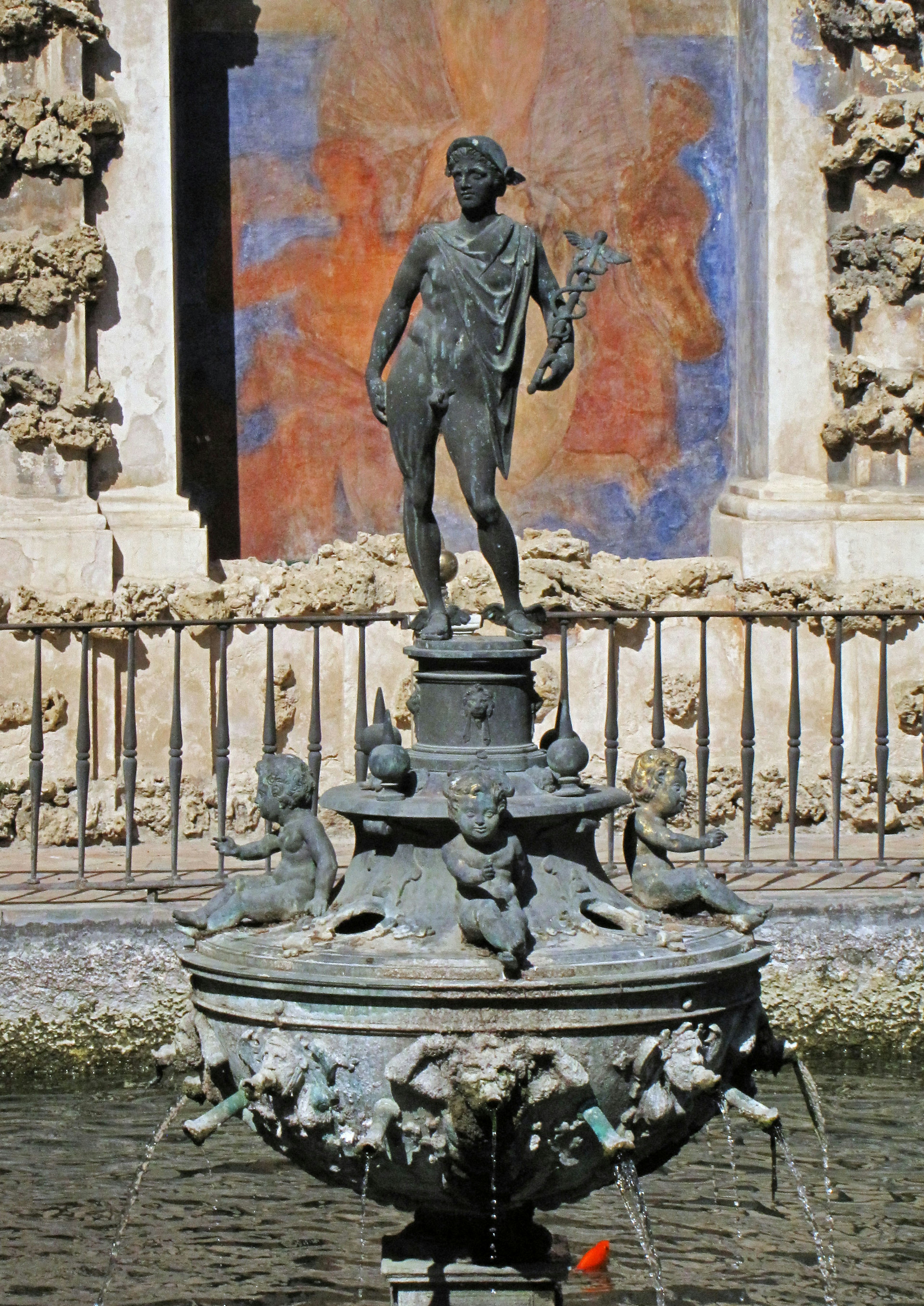 Bronze statue on a fountain with a blue mural backdrop