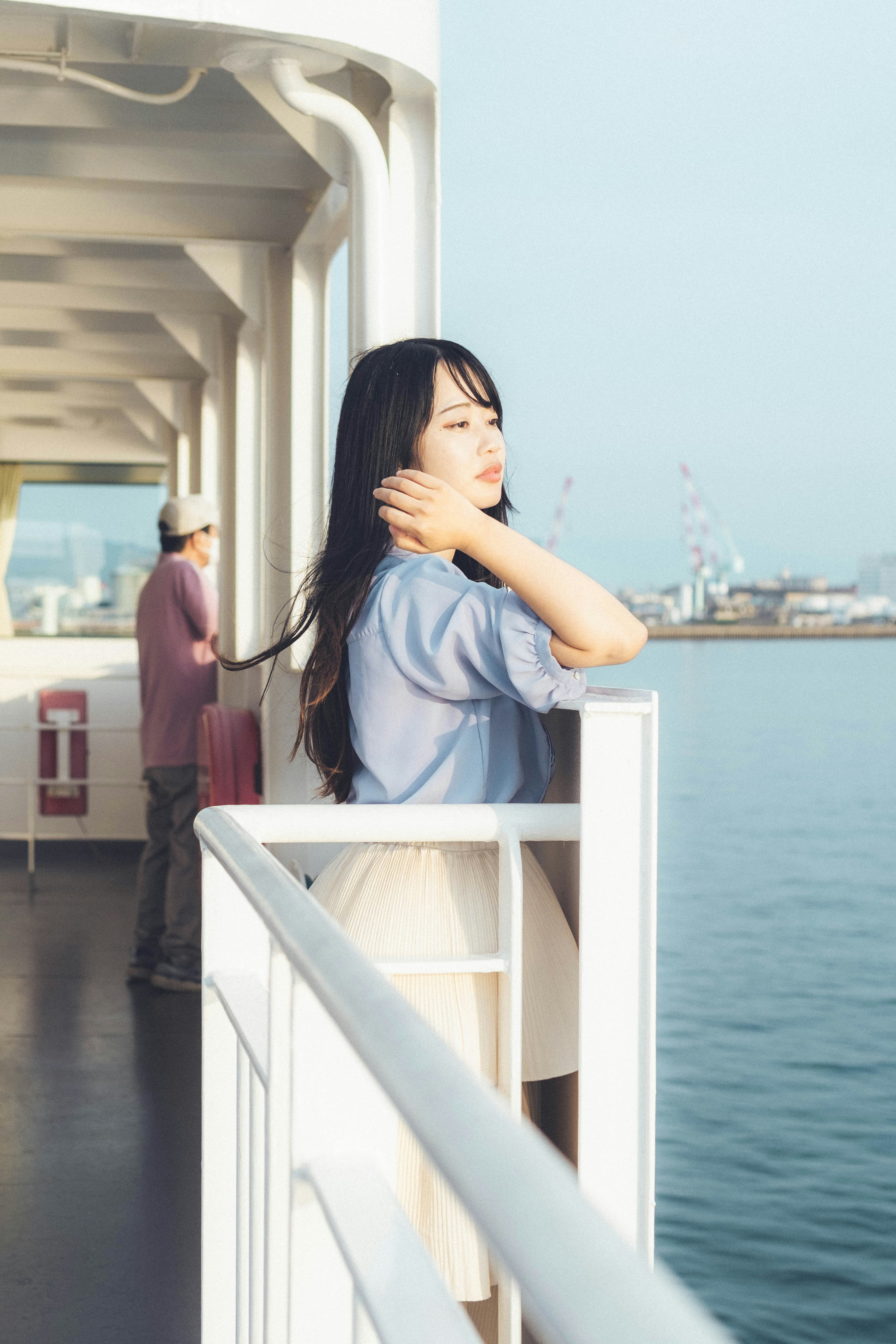 Profile view of a woman relaxing on a ship deck with a calm sea in the background