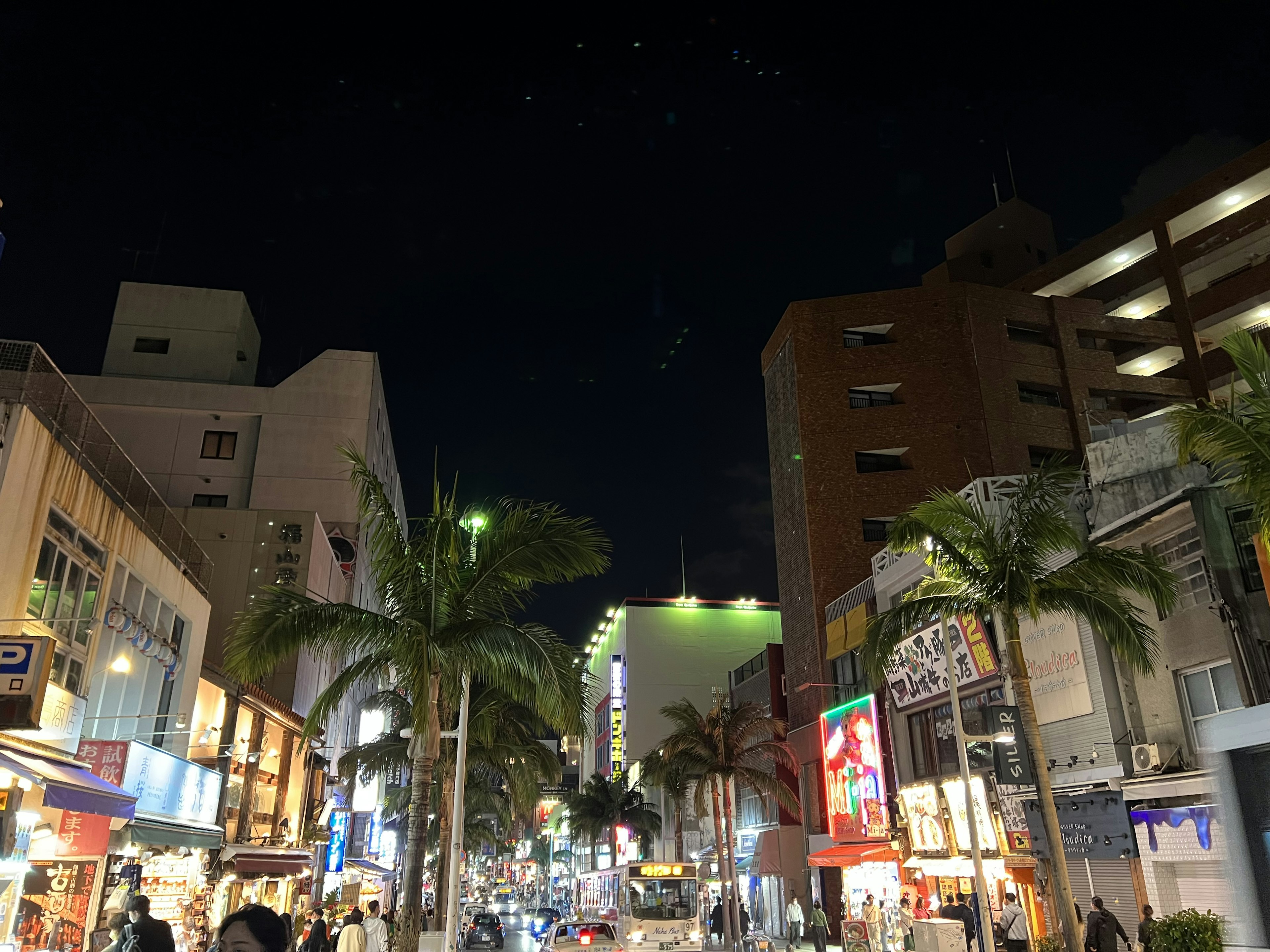 Escena nocturna de la ciudad con palmeras y letreros de neón