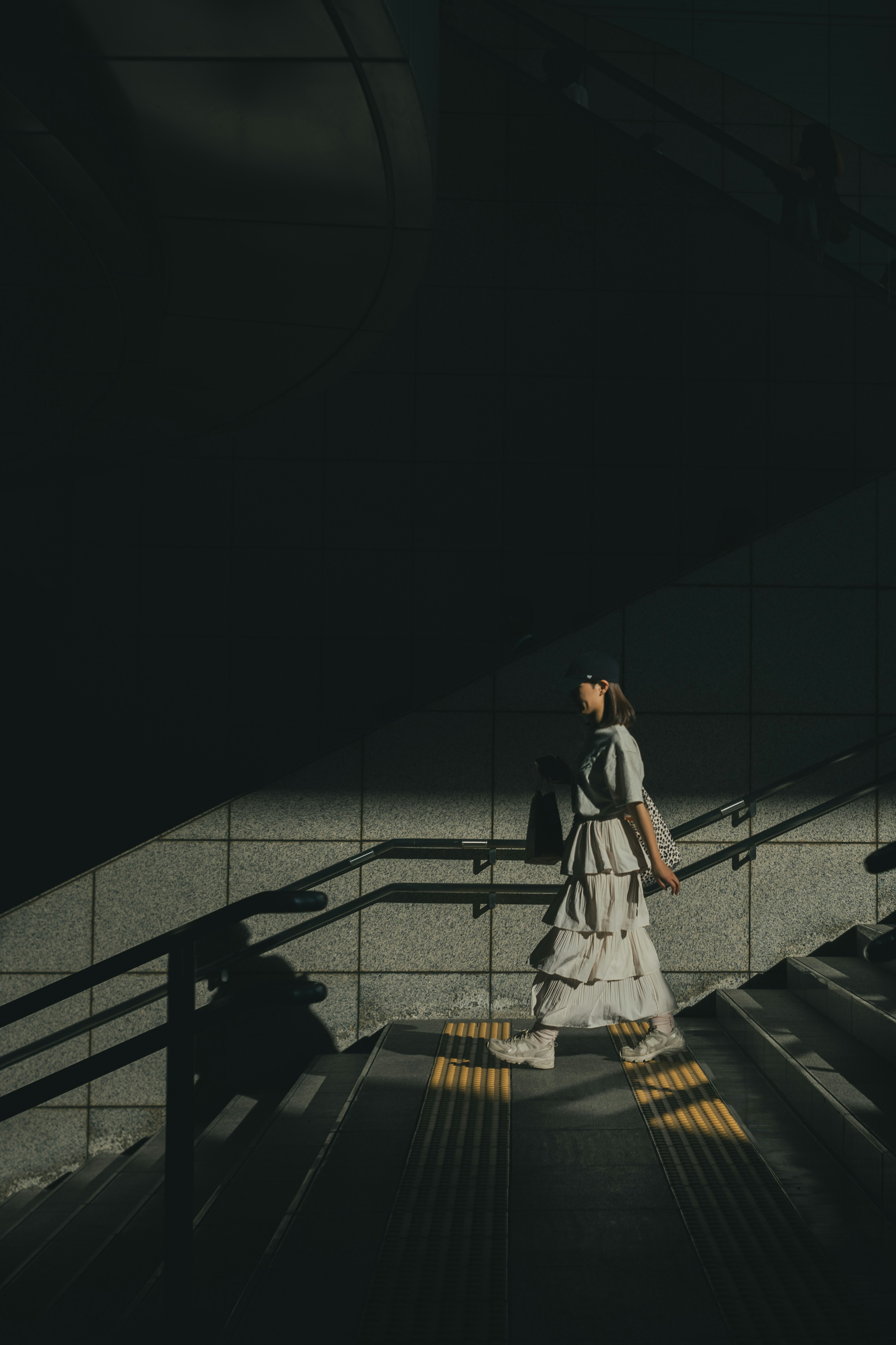 Eine Frau, die eine dunkle Treppe mit markanten Schatten hinuntergeht