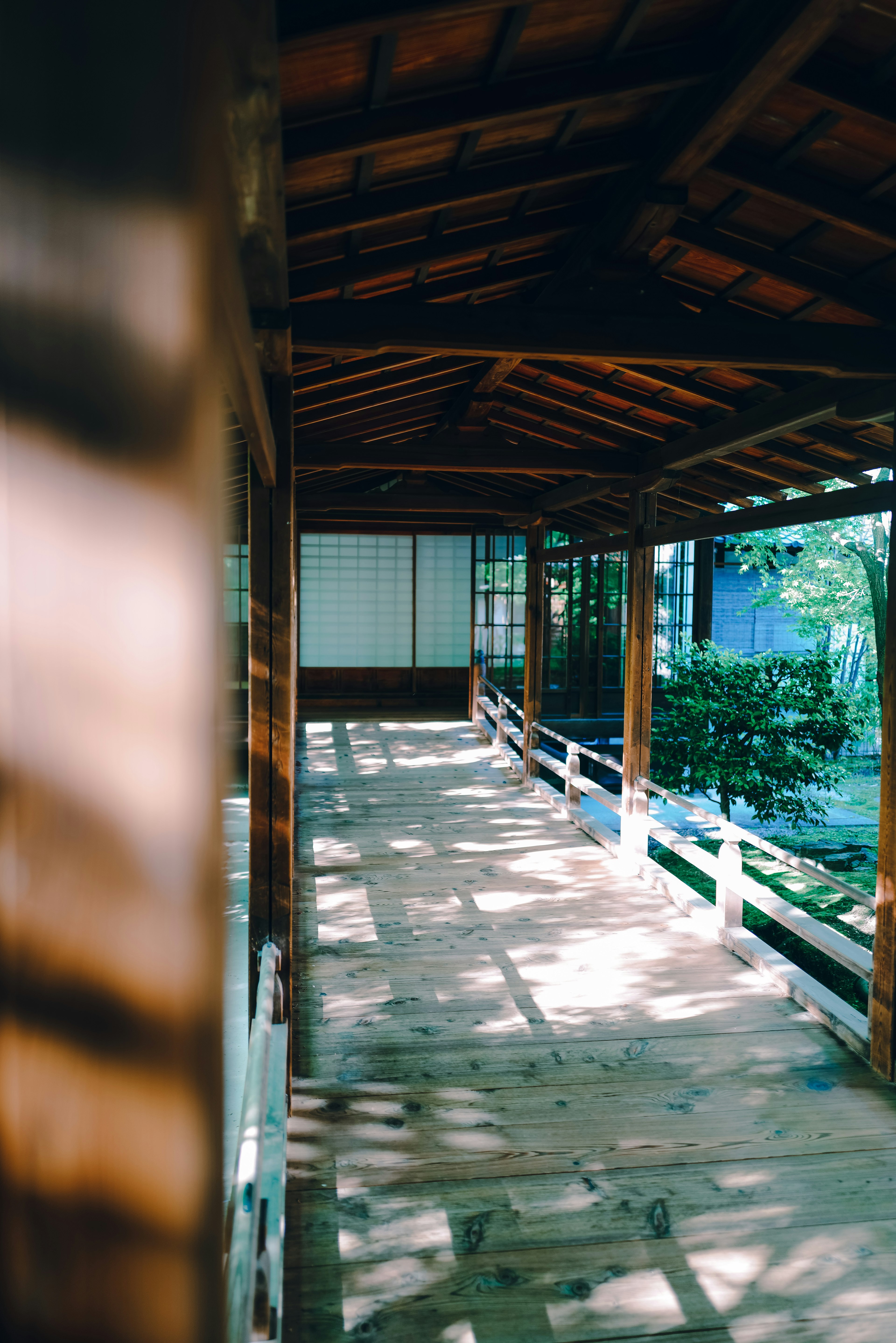 Couloir en bois d'un bâtiment japonais traditionnel avec un toit et une lumière naturelle