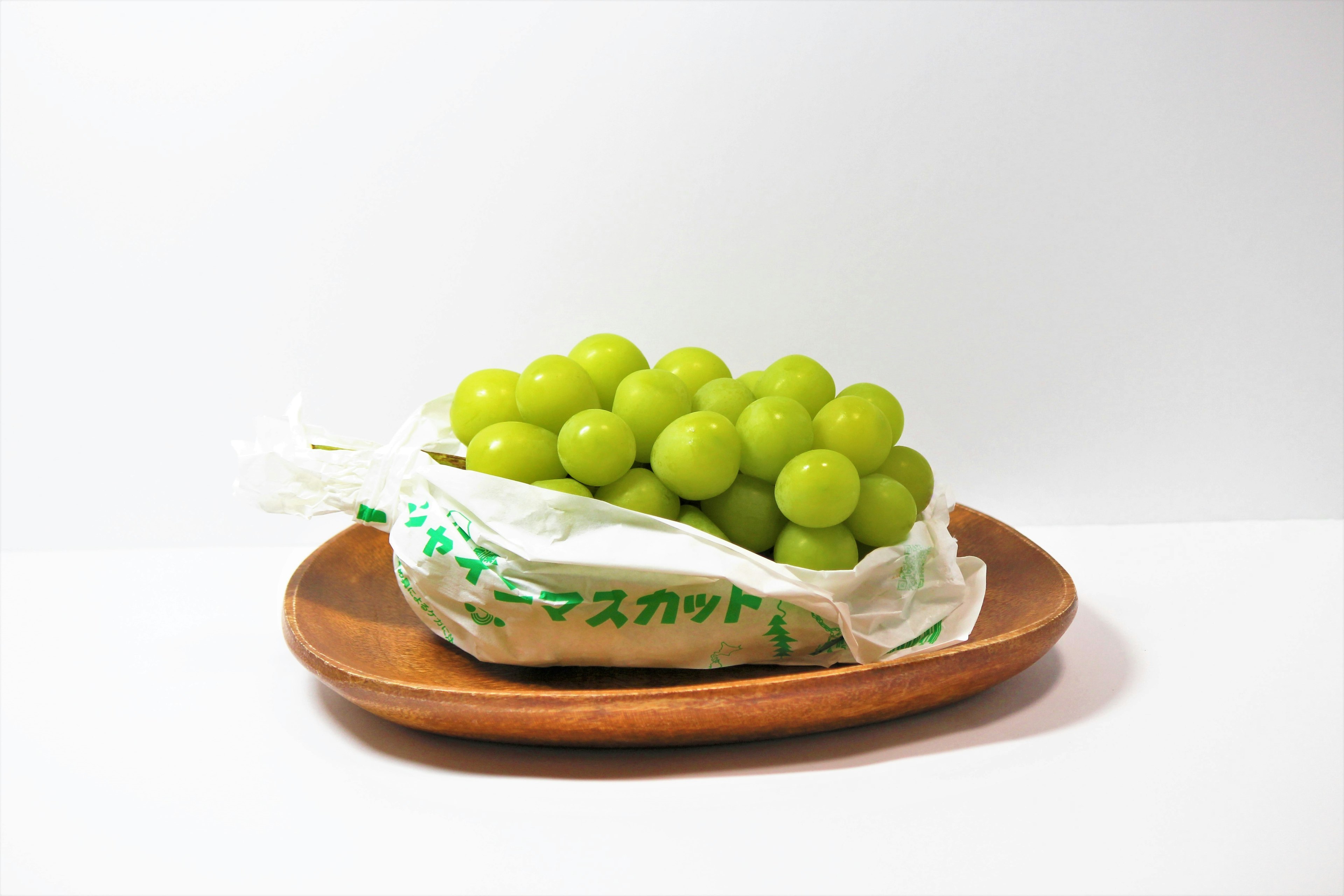 A package of green grapes on a wooden plate