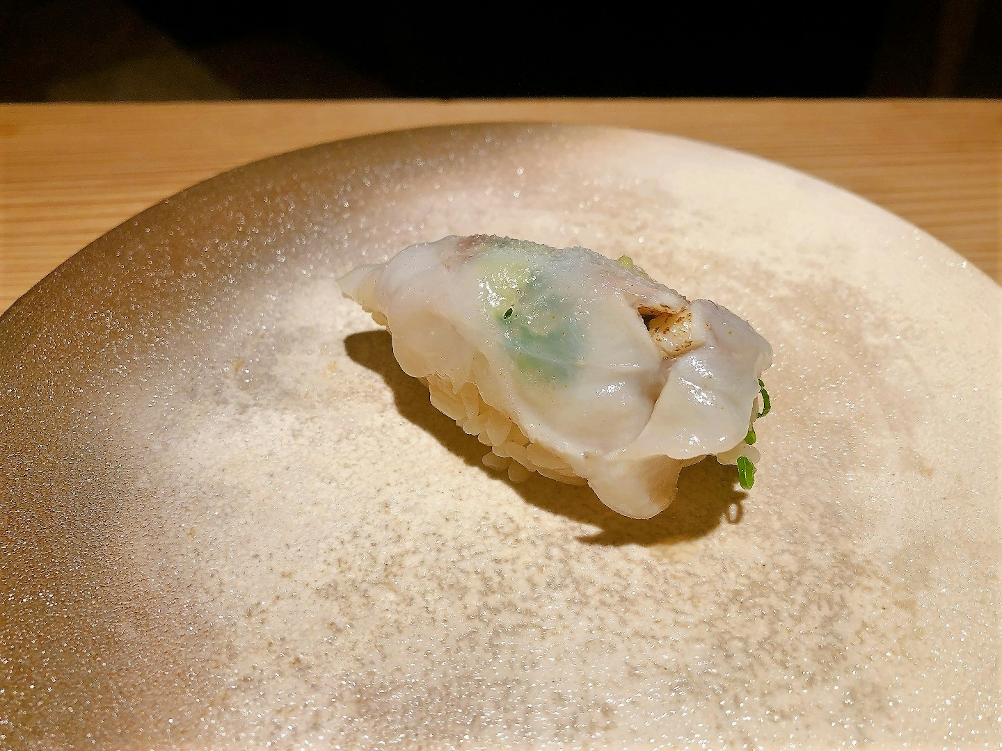 A translucent sushi piece on a beautiful gold plate