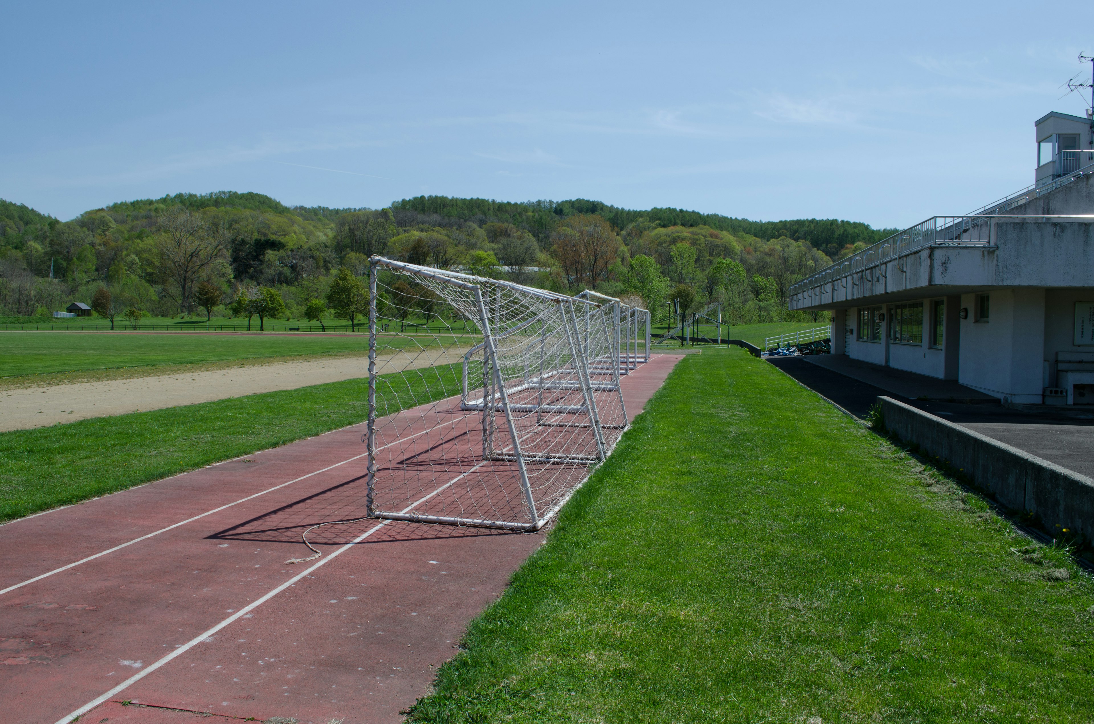 Fußballtor auf einem Sportplatz mit lebendigem grünem Gras und klarem blauen Himmel