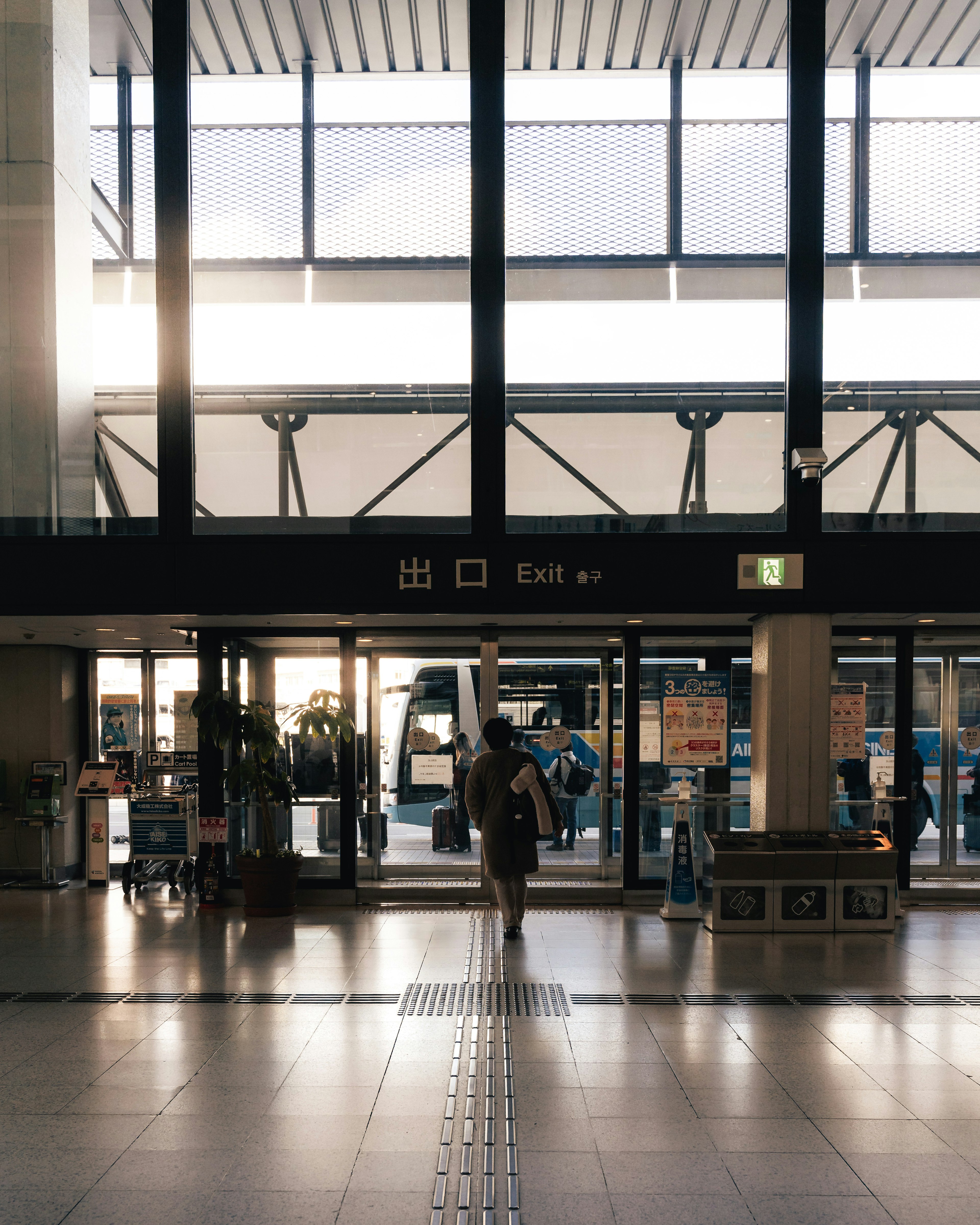 People walking towards the exit of a station with bright natural light coming in