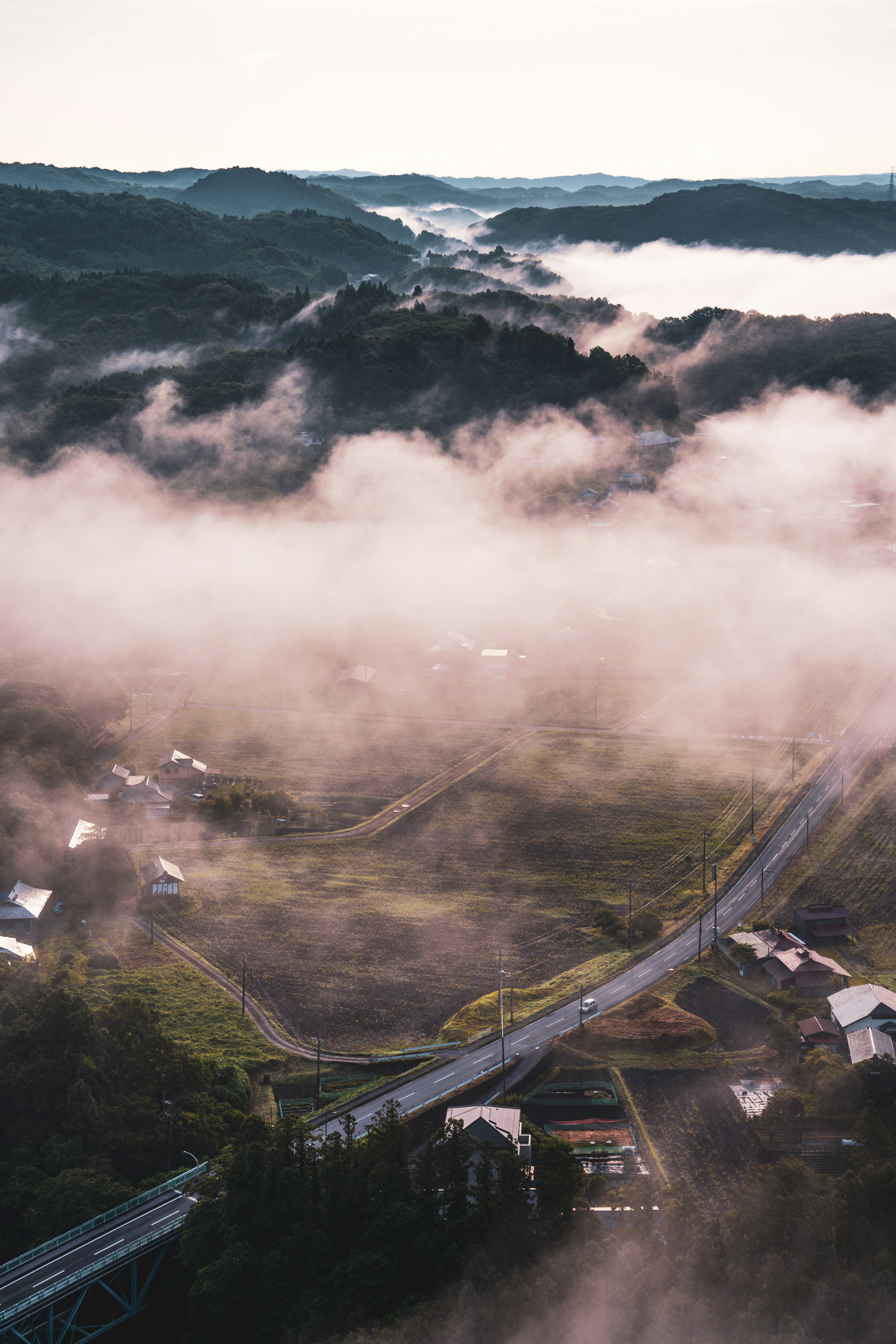 Vista aérea de colinas cubiertas de niebla y una carretera sinuosa