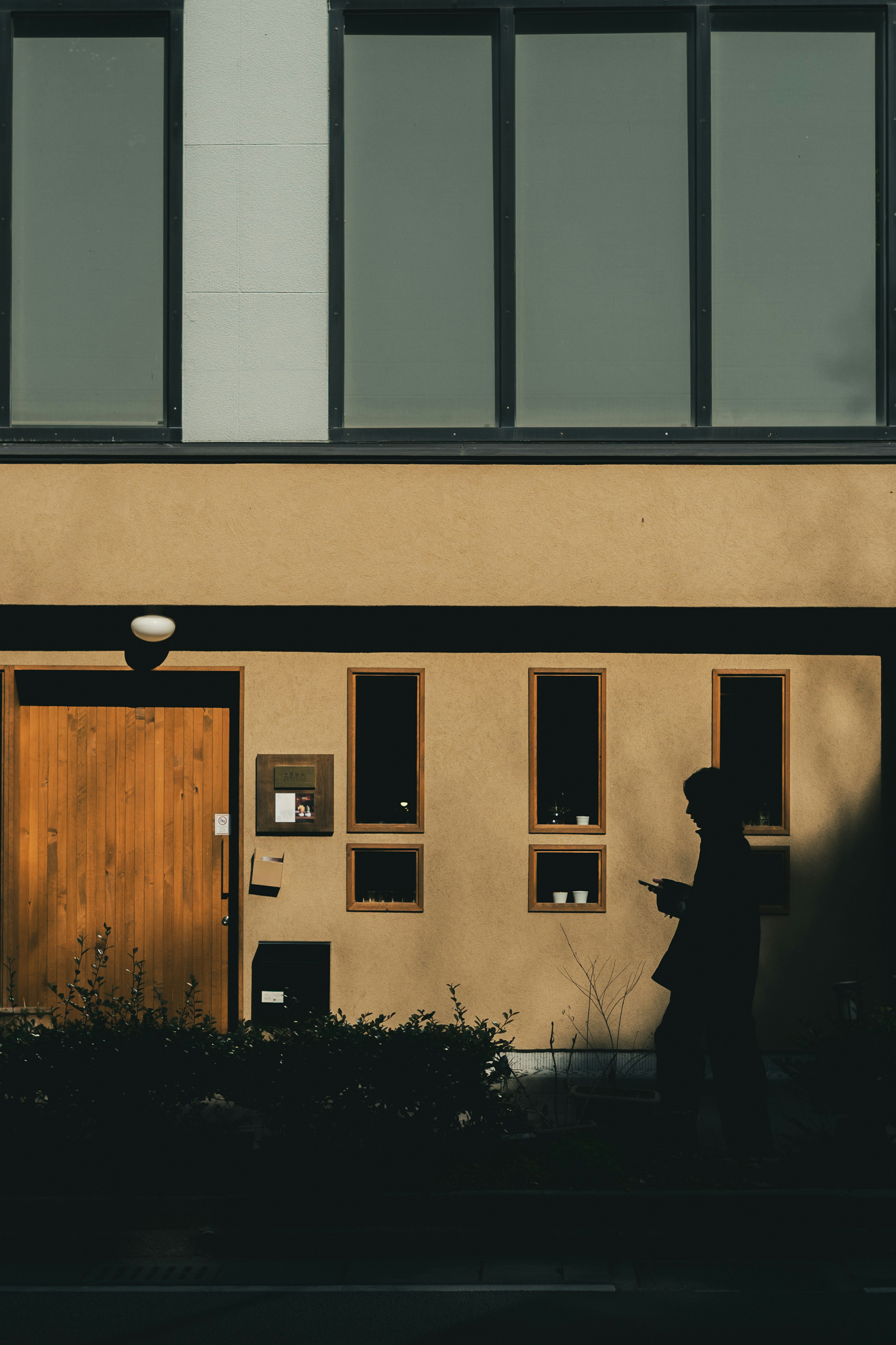 Schatten einer Person vor einem Gebäude mit Holztür