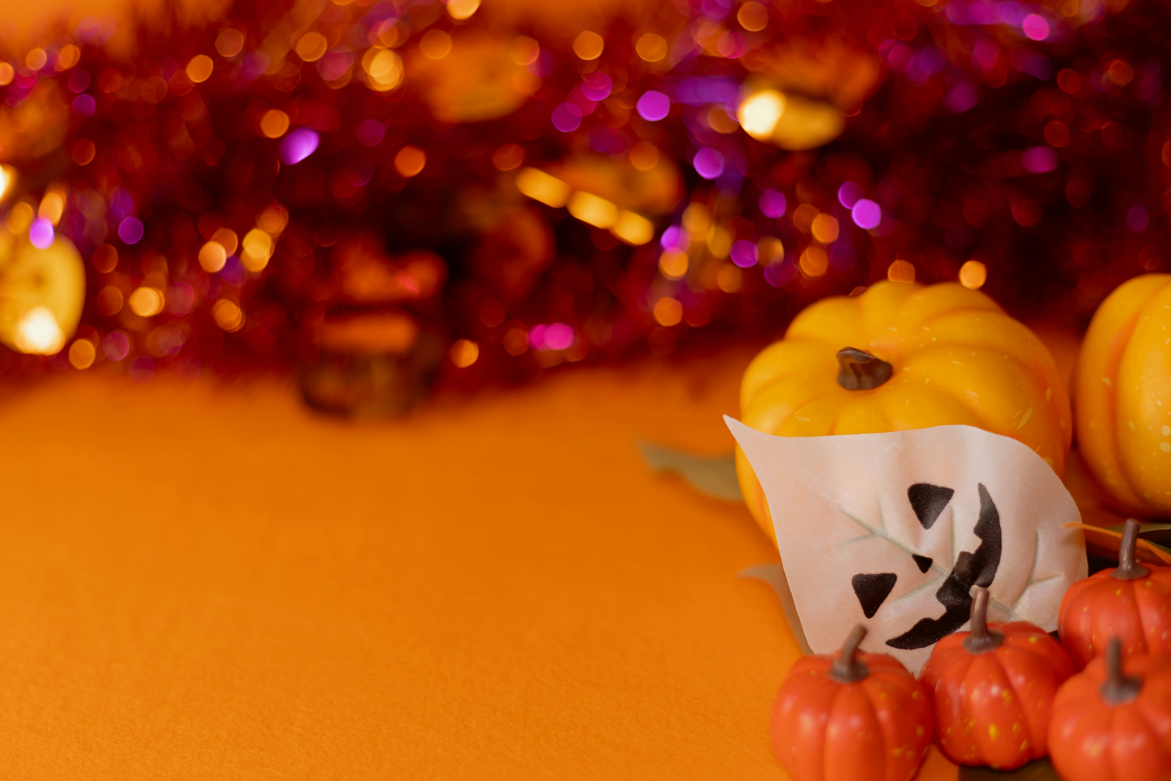 Decoraciones de Halloween con calabazas y una máscara espeluznante sobre un fondo naranja