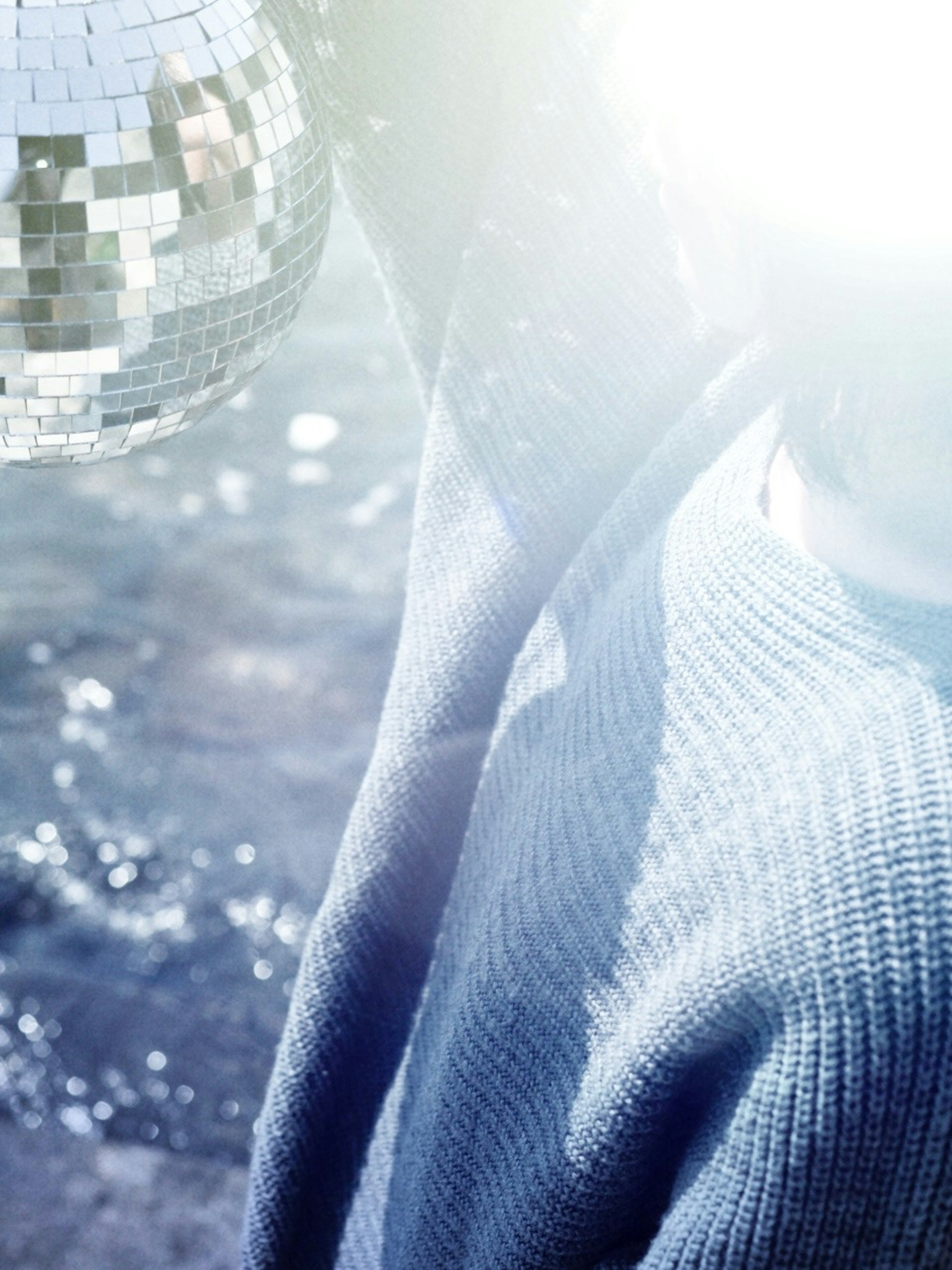 A person holding a disco ball with bright light creating a dreamy atmosphere