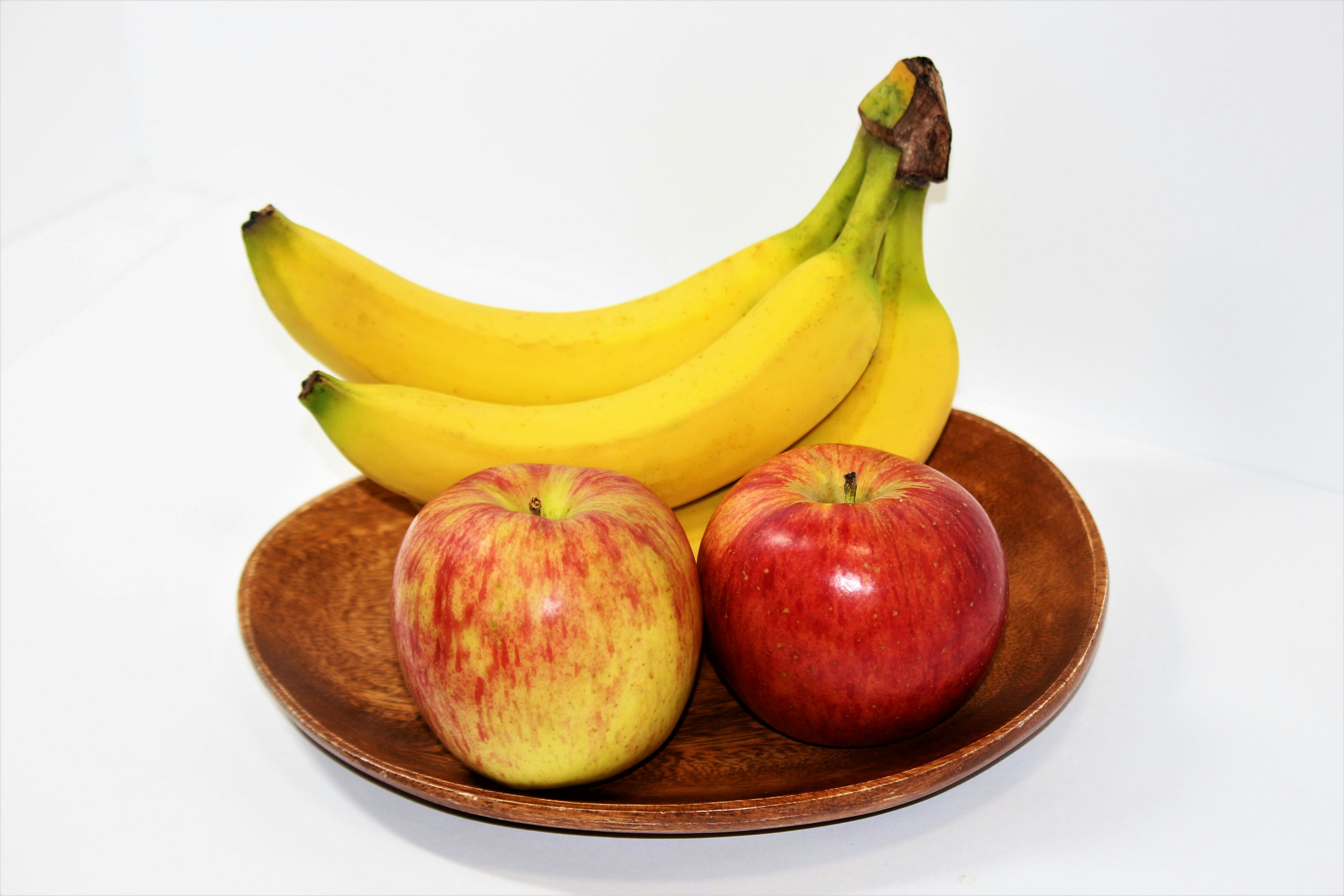 Two apples and three bananas on a wooden plate