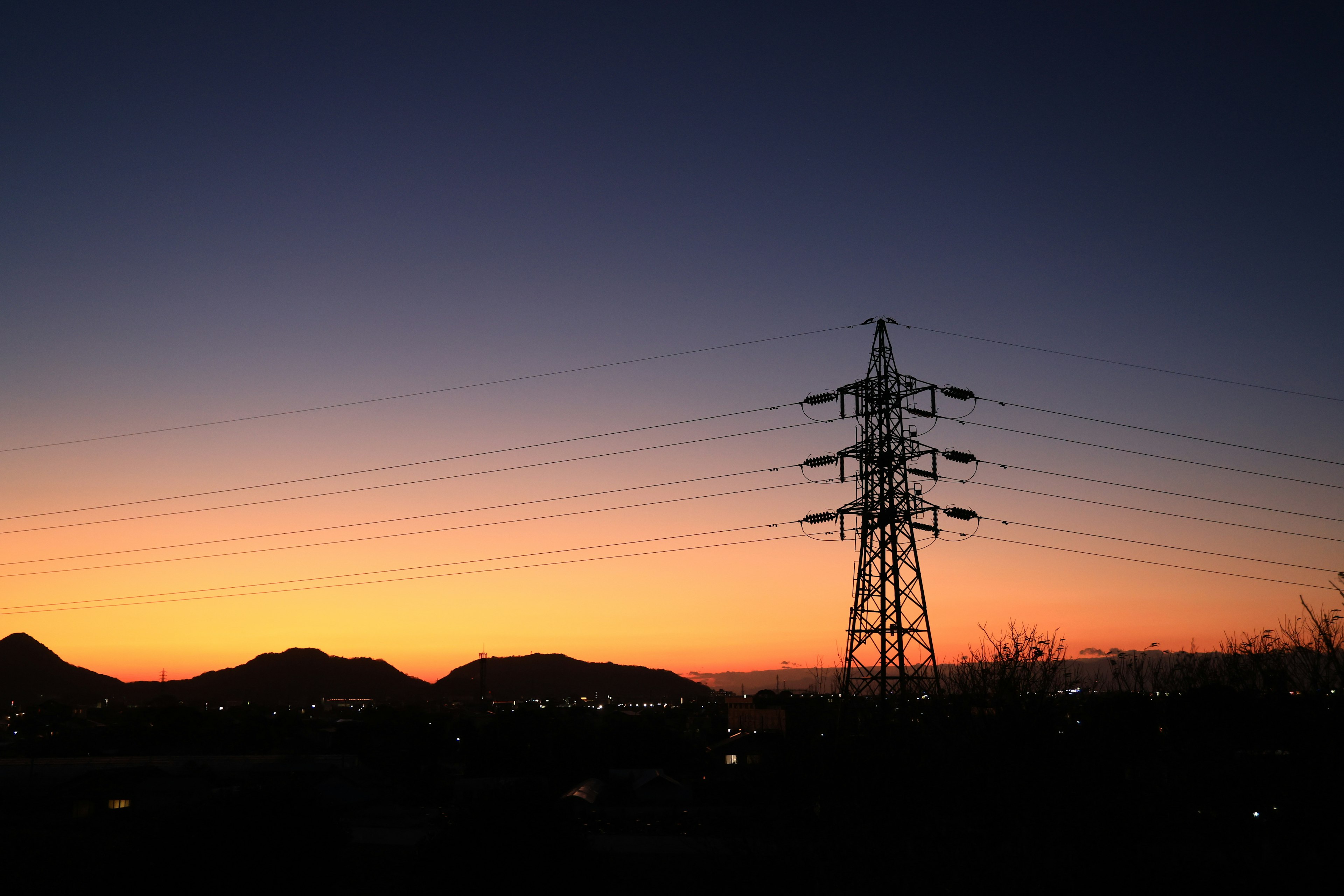 Silhouette of a power tower against a vibrant sunset sky