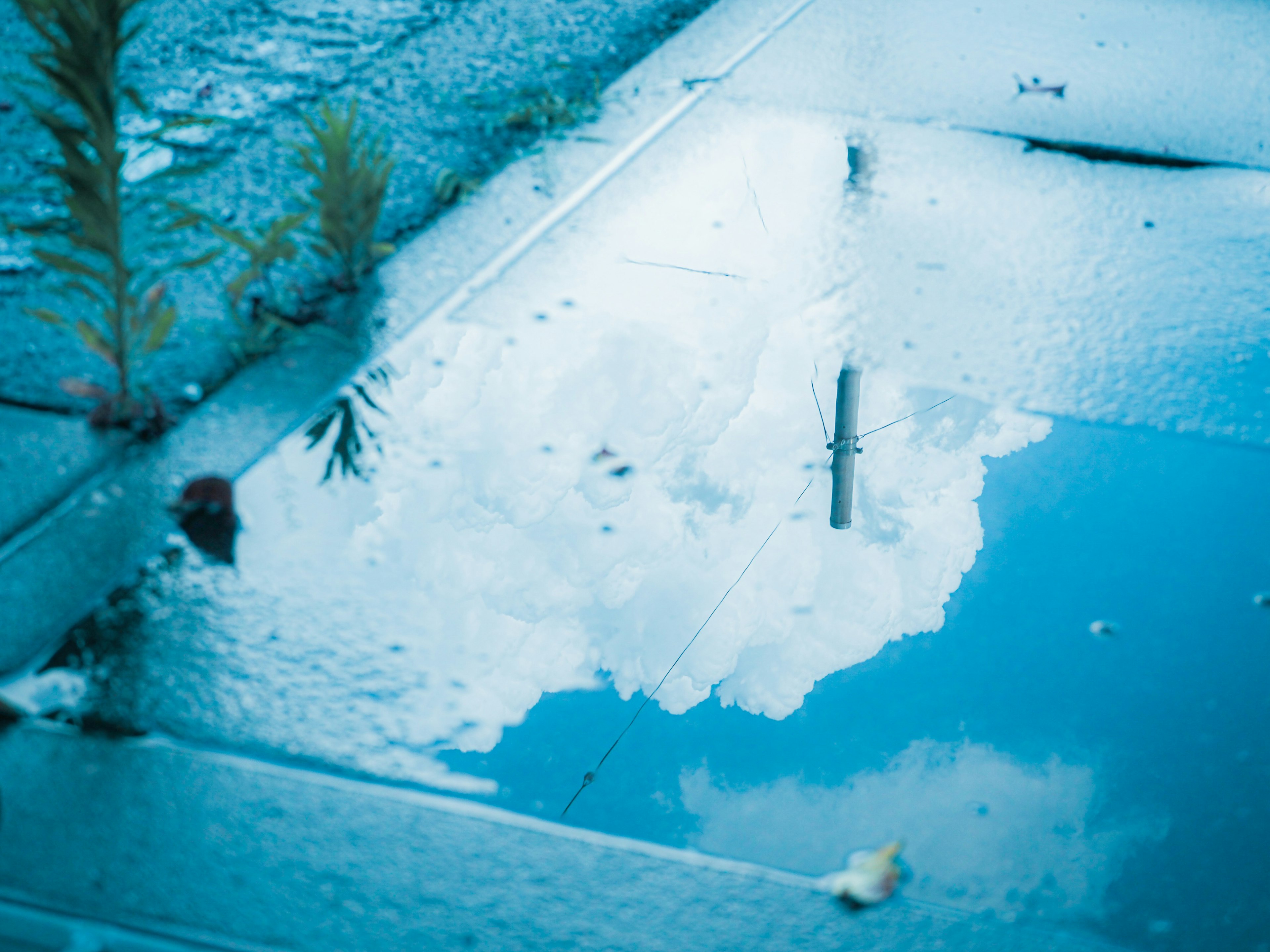 Reflexion des blauen Himmels und der Wolken in einer Pfütze