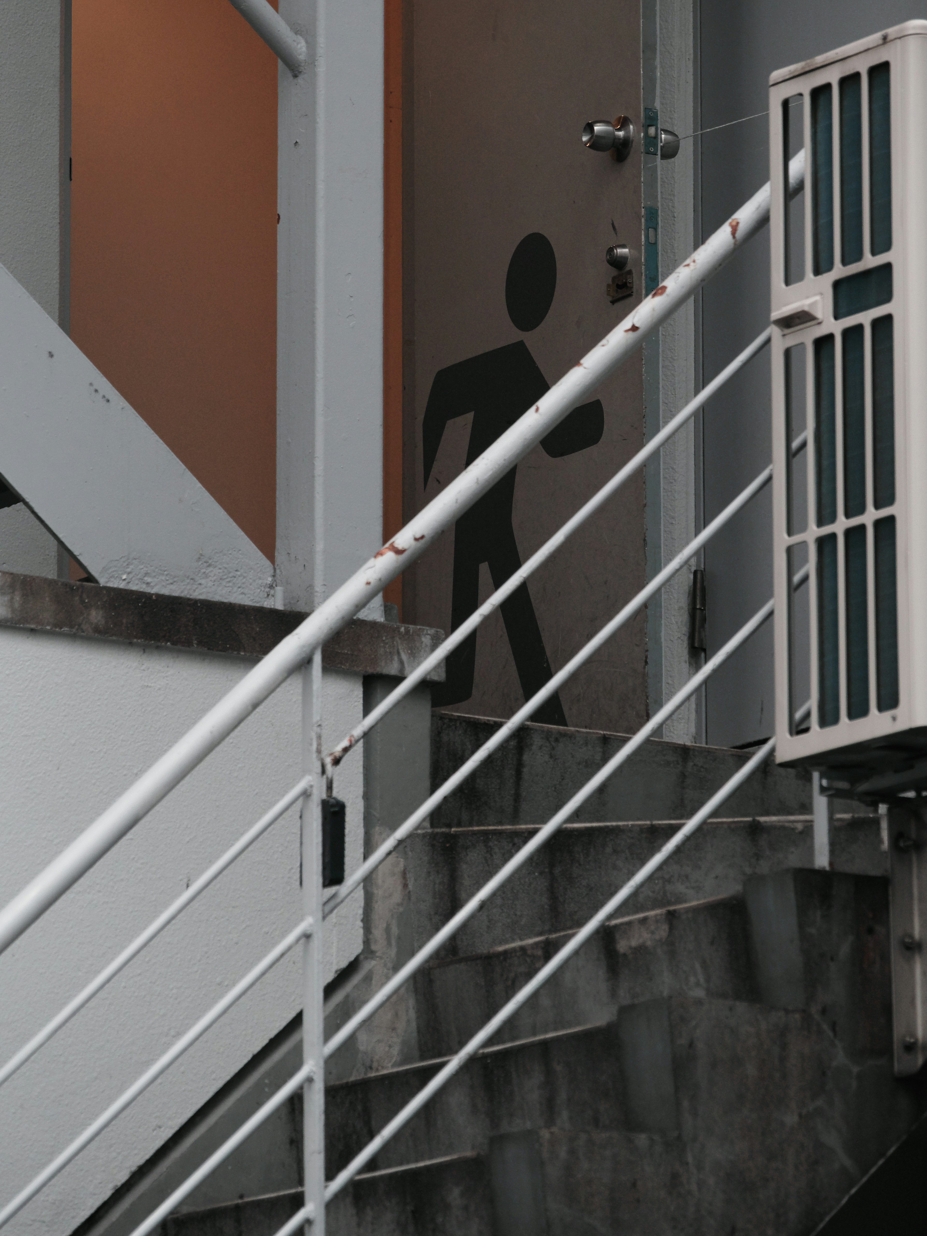 Silueta de una persona frente a una puerta junto a una escalera