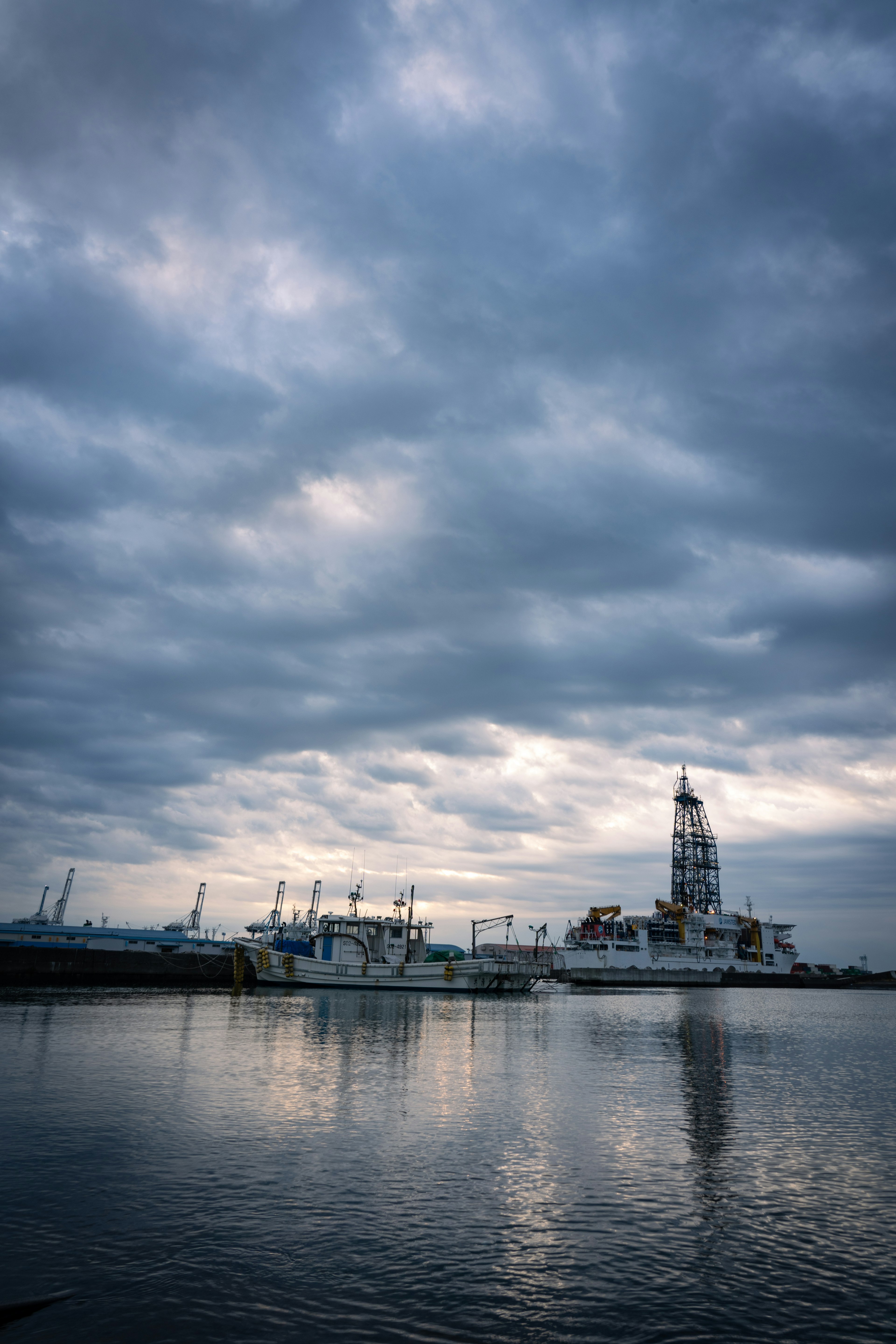 A harbor scene featuring docked boats and a cloudy sky