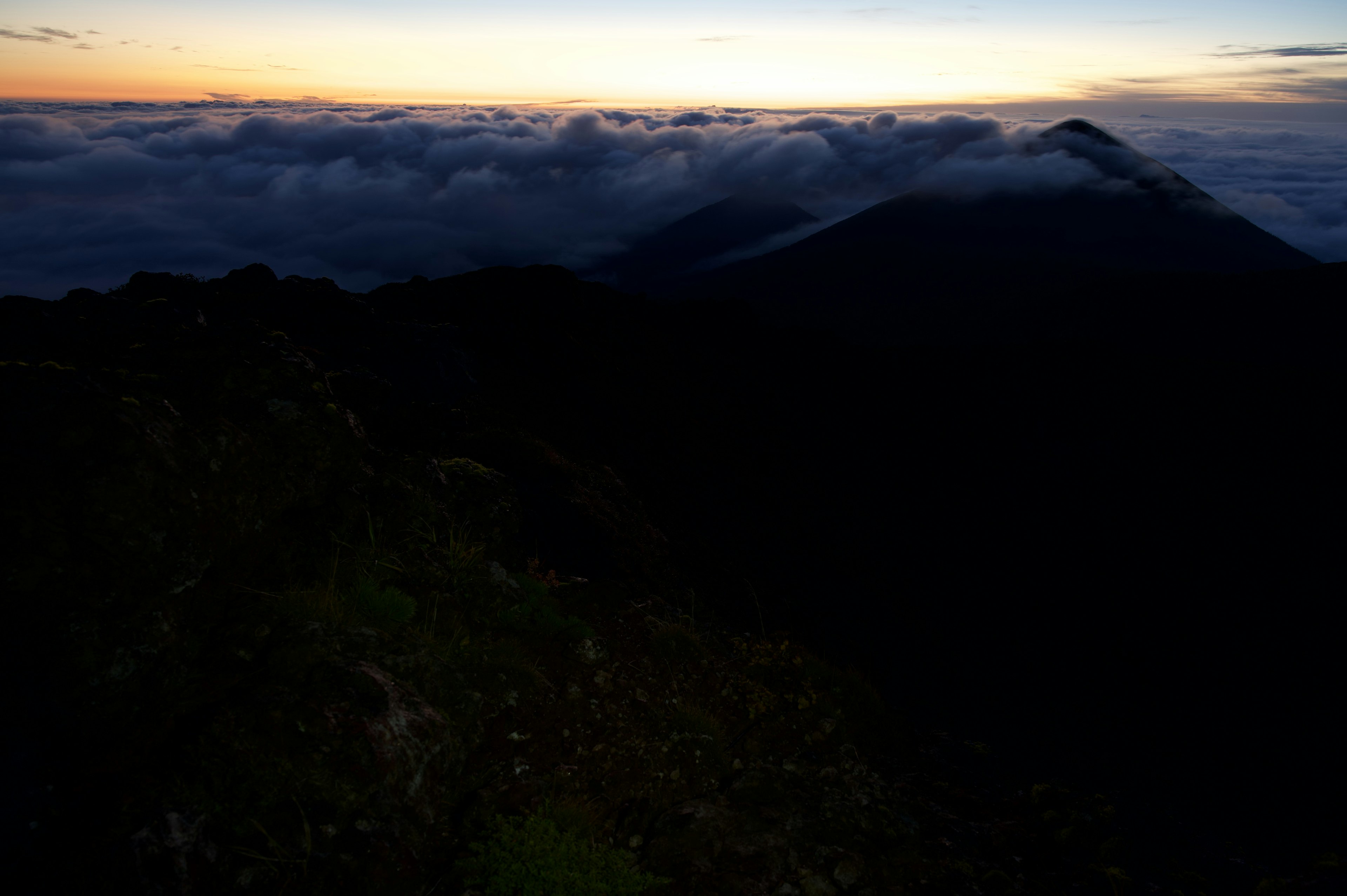 Scenic view of mountain silhouette and sea of clouds during sunset