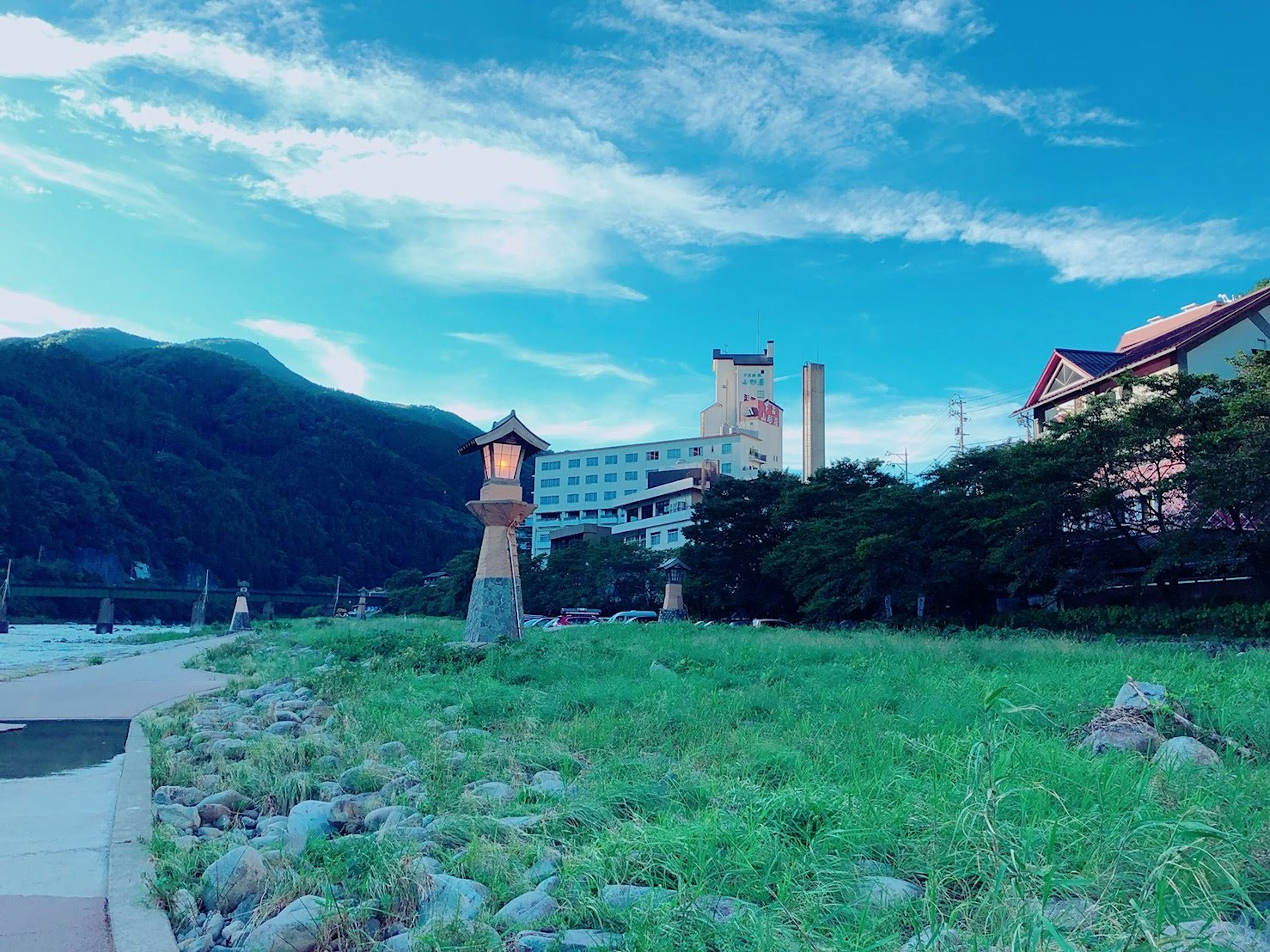 Coastal view featuring a lighthouse and buildings with mountains in the background and a blue sky