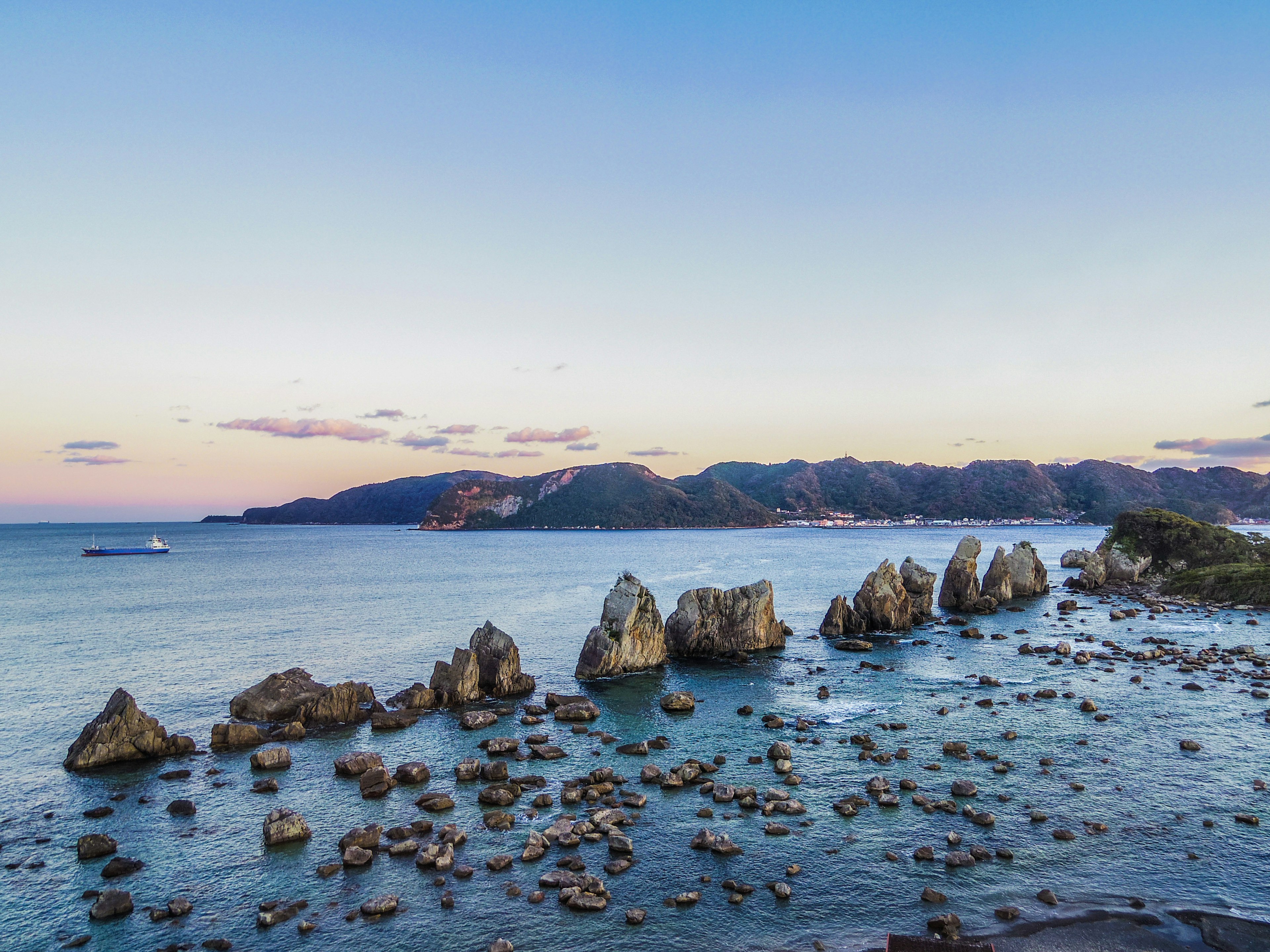 海岸线上的岩石形成与平静的海洋和日落天空