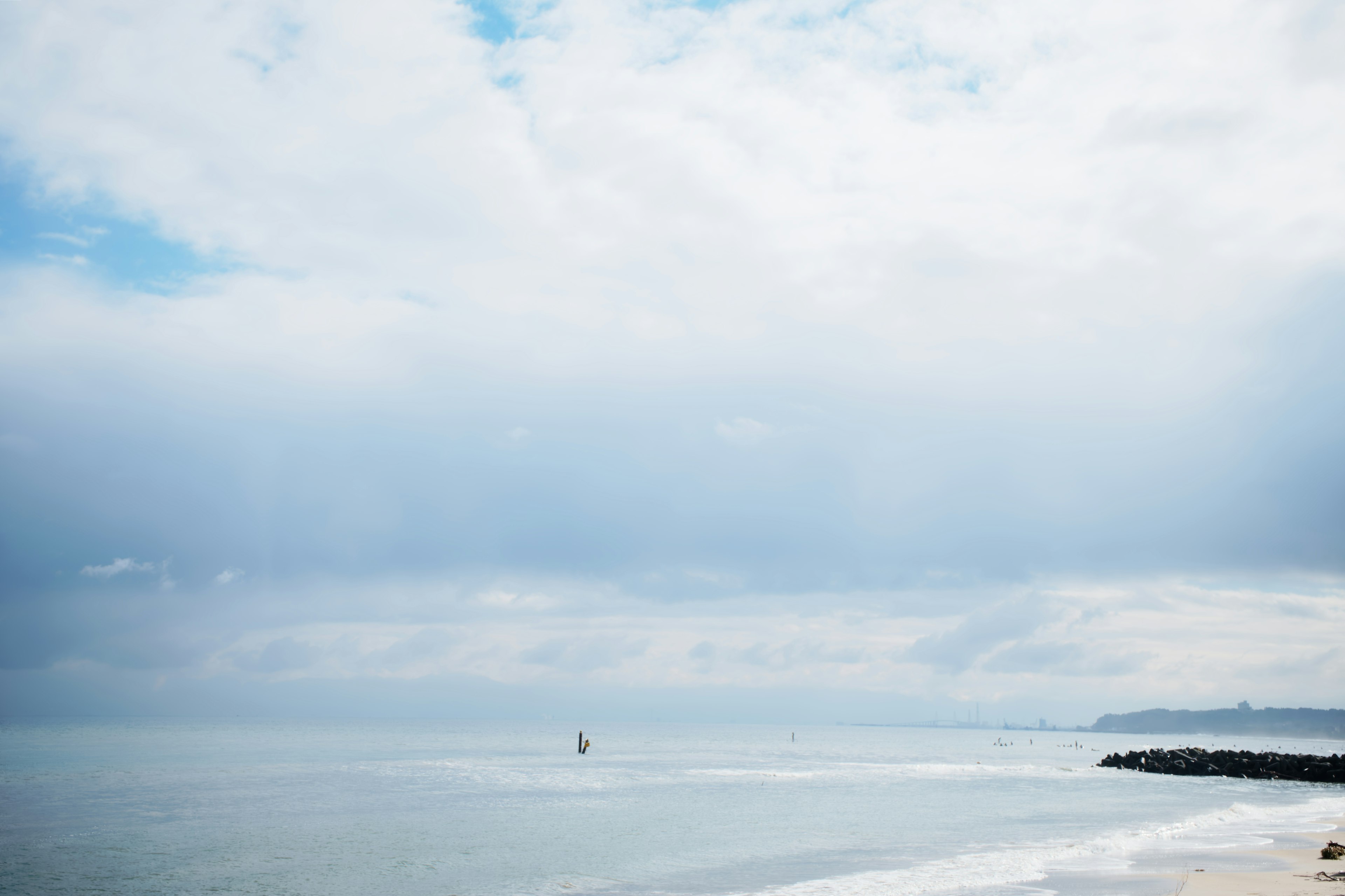 A serene seascape with a small sailboat on calm waters under a blue sky