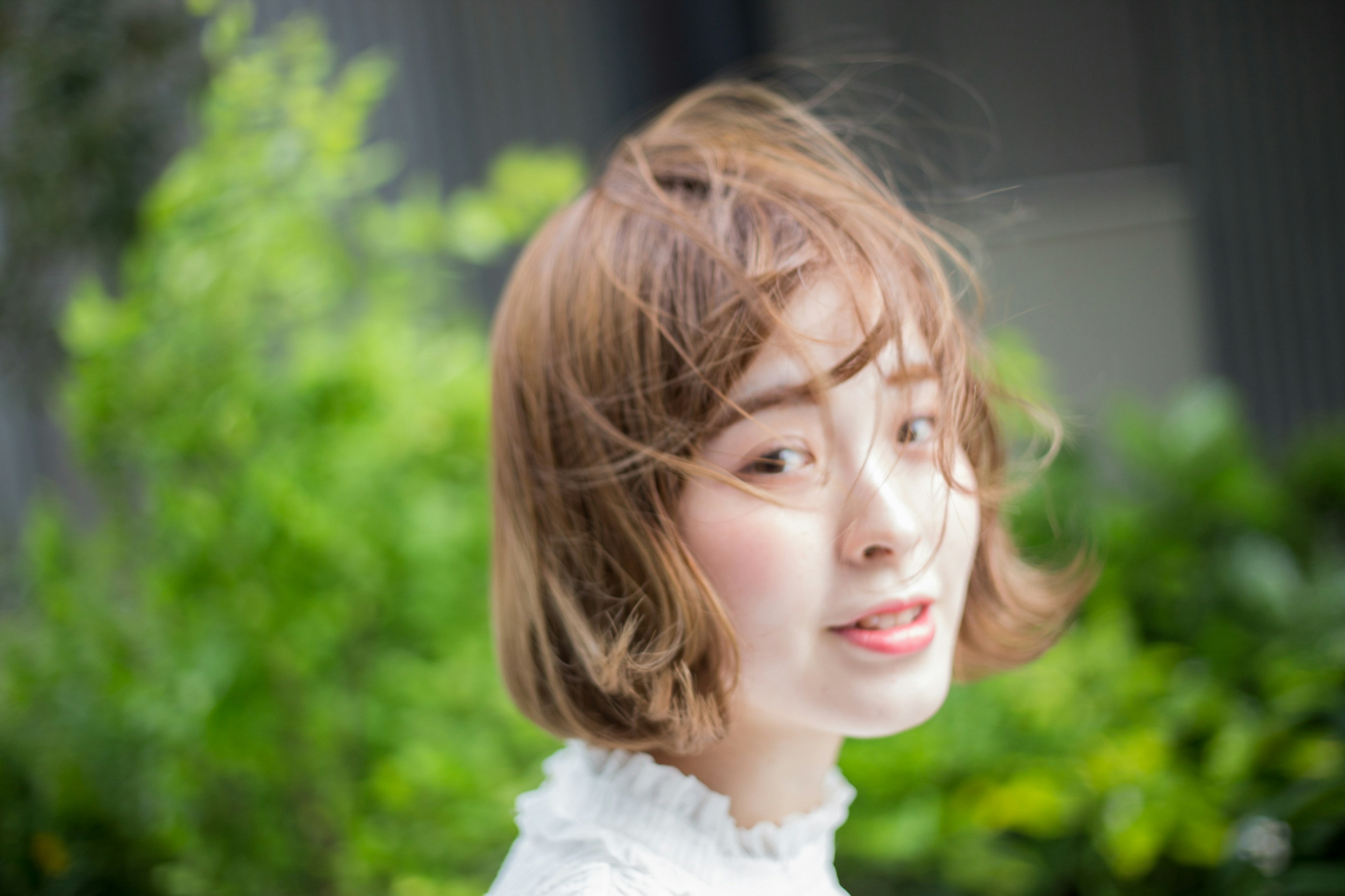 Portrait of a woman with windblown hair against a green background