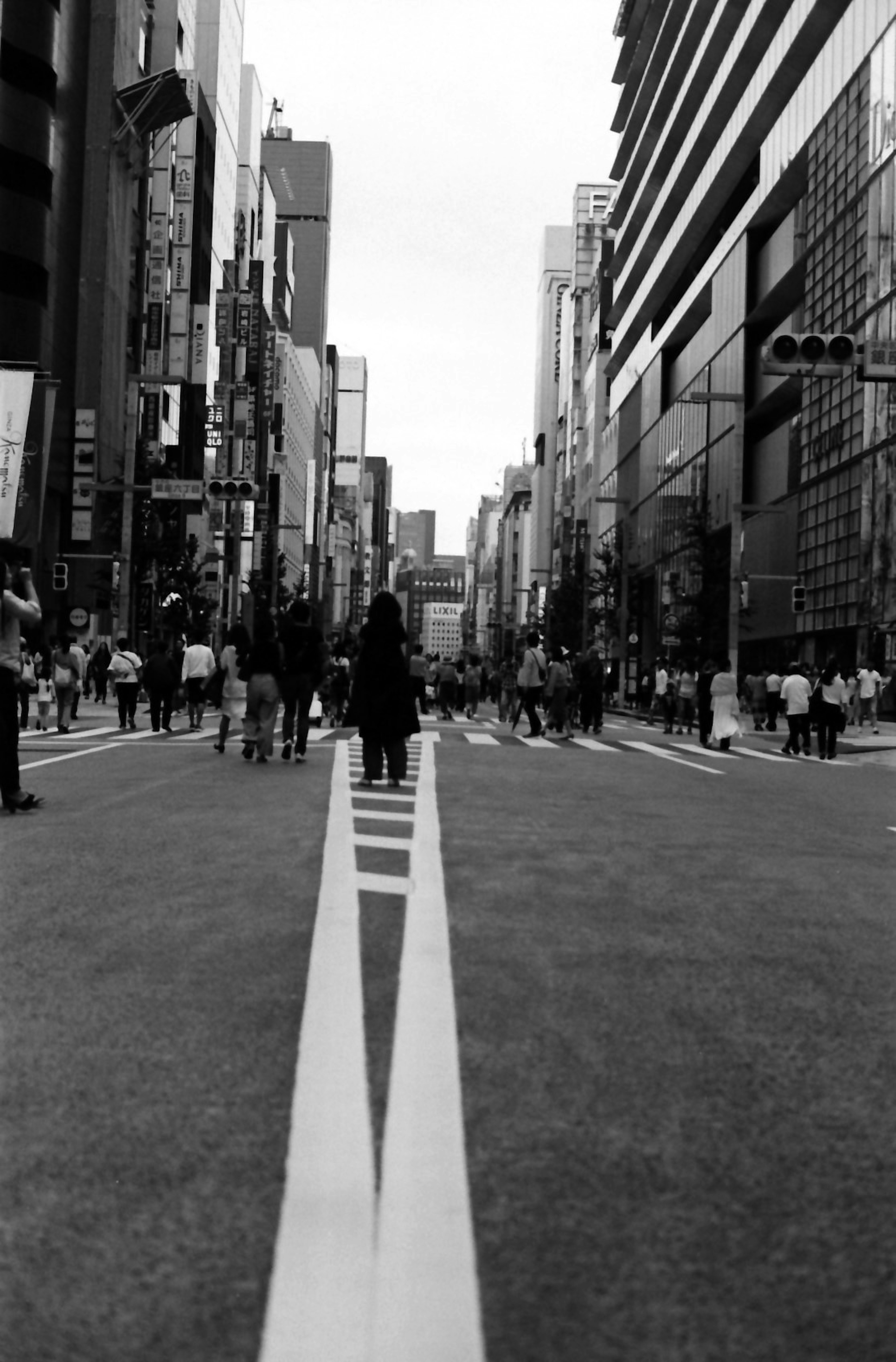 Black and white street scene with people walking and urban buildings