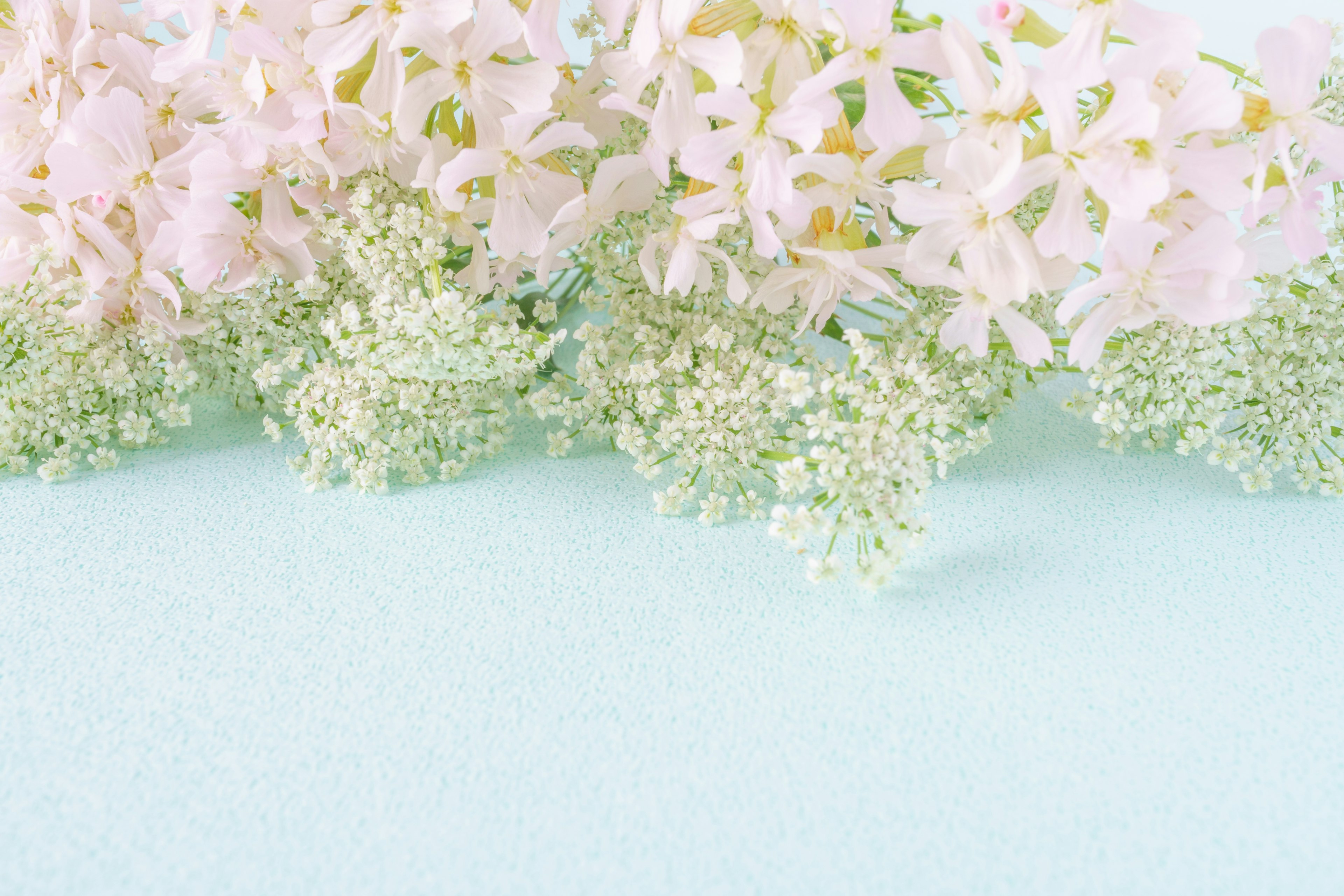 Un ramo de flores rosas y blancas dispuesto sobre una tela verde menta