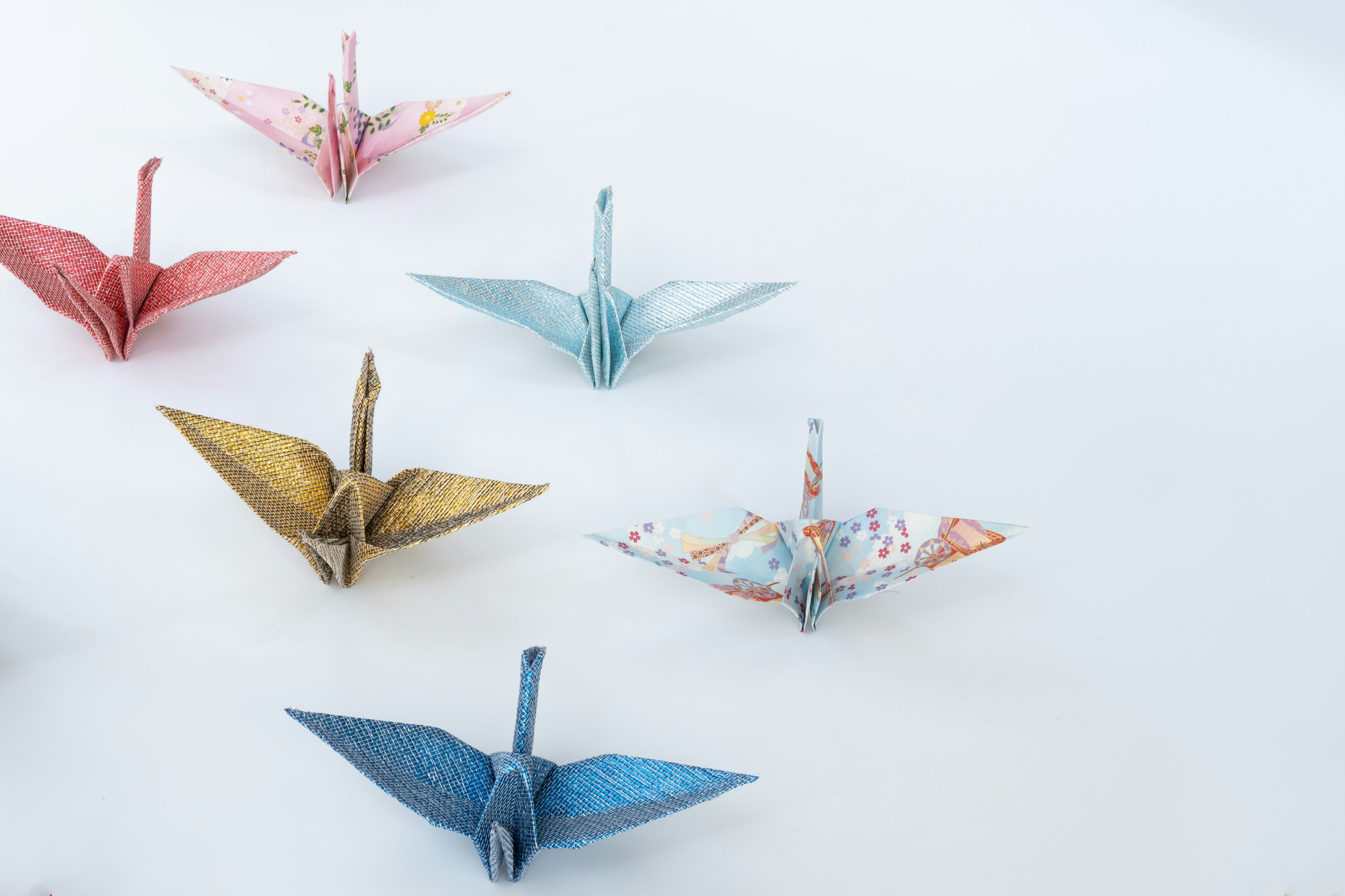 A colorful arrangement of origami cranes on a white background