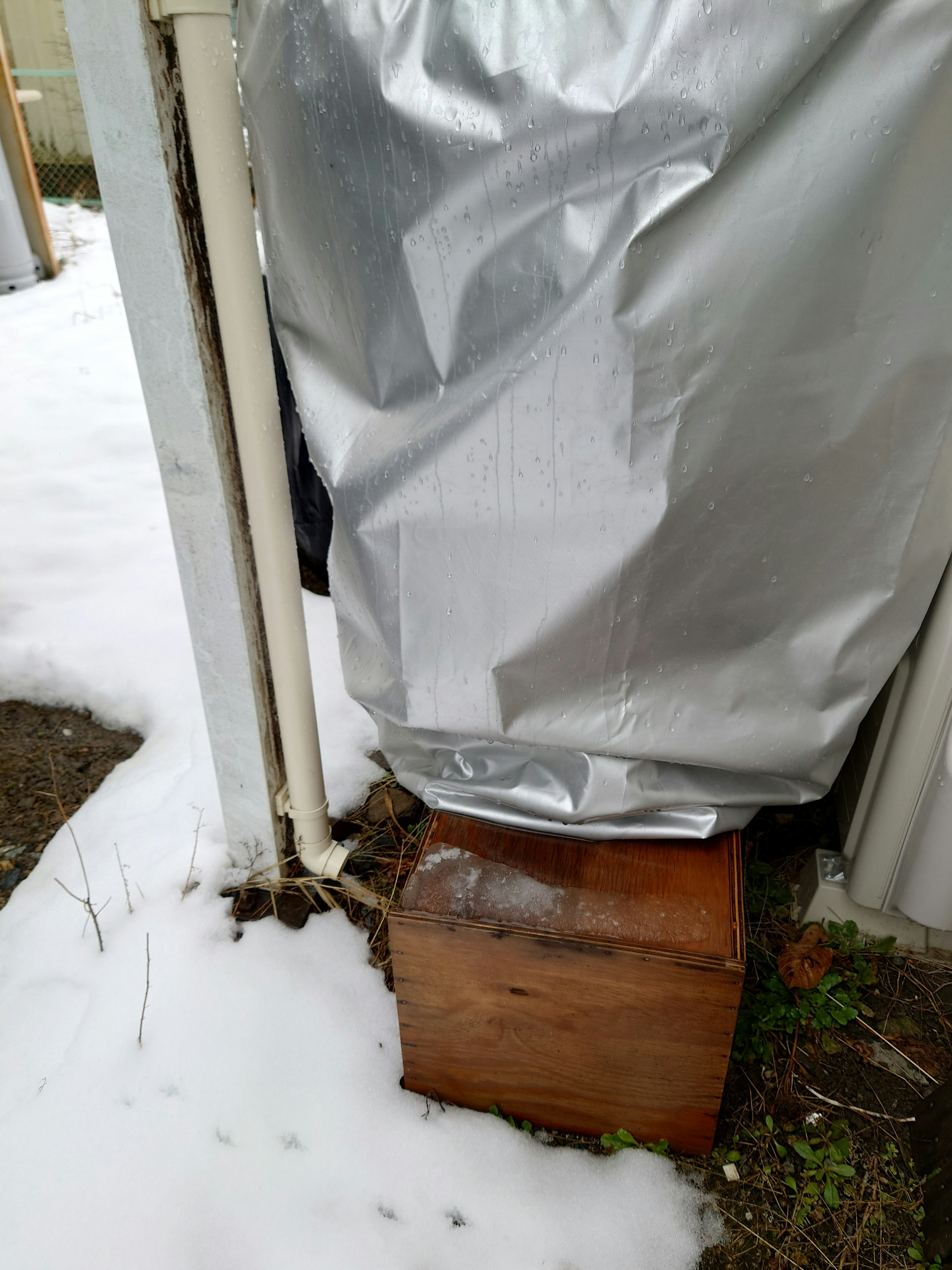 Objekt mit silbernem Blatt bedeckt und Holzkiste auf Schnee